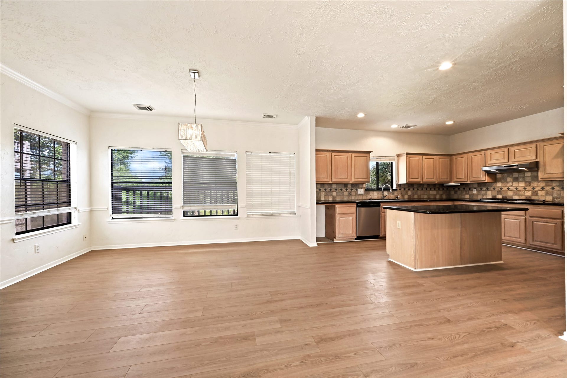 2607 Sailboat Drive, Houston, TX 77058 Spacious open-concept kitchen and dining area featuring warm wood floors, abundant natural light from multiple windows, modern pendant lighting, and ample cabinetry with a large central island perfect for gatherings.