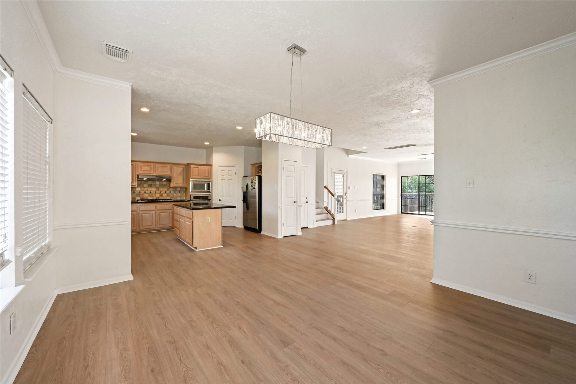 2607 Sailboat Drive, Houston, TX 77058 Spacious open-concept living area featuring elegant hardwood floors, a modern chandelier, and a sleek kitchen with ample cabinetry and stainless steel appliances.