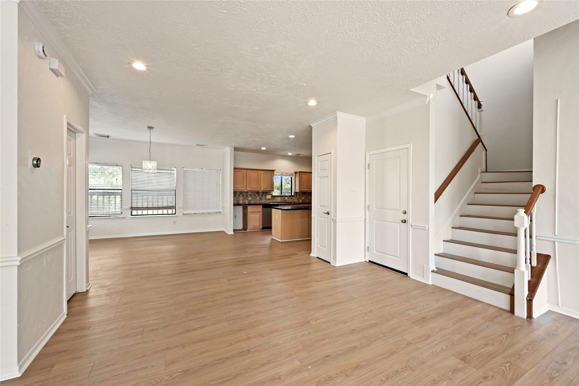 2607 Sailboat Drive, Houston, TX 77058 Spacious open-concept living area with elegant wood flooring, abundant natural light, and a modern kitchen featuring warm cabinetry. The staircase leads to the upper level, adding a touch of sophistication.