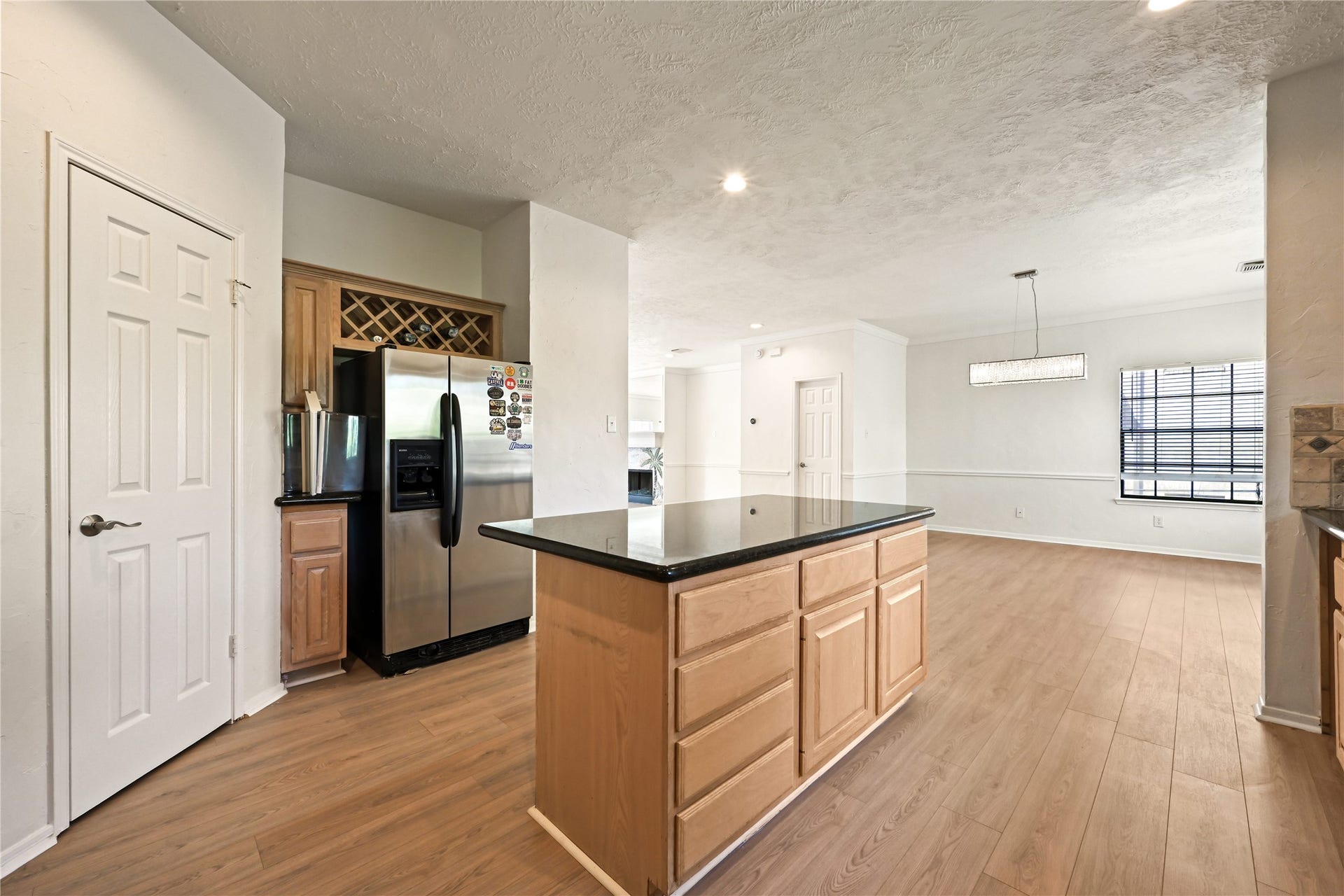 2607 Sailboat Drive, Houston, TX 77058 Open kitchen and dining area featuring sleek hardwood floors, a modern stainless steel refrigerator, and a large island with ample storage.