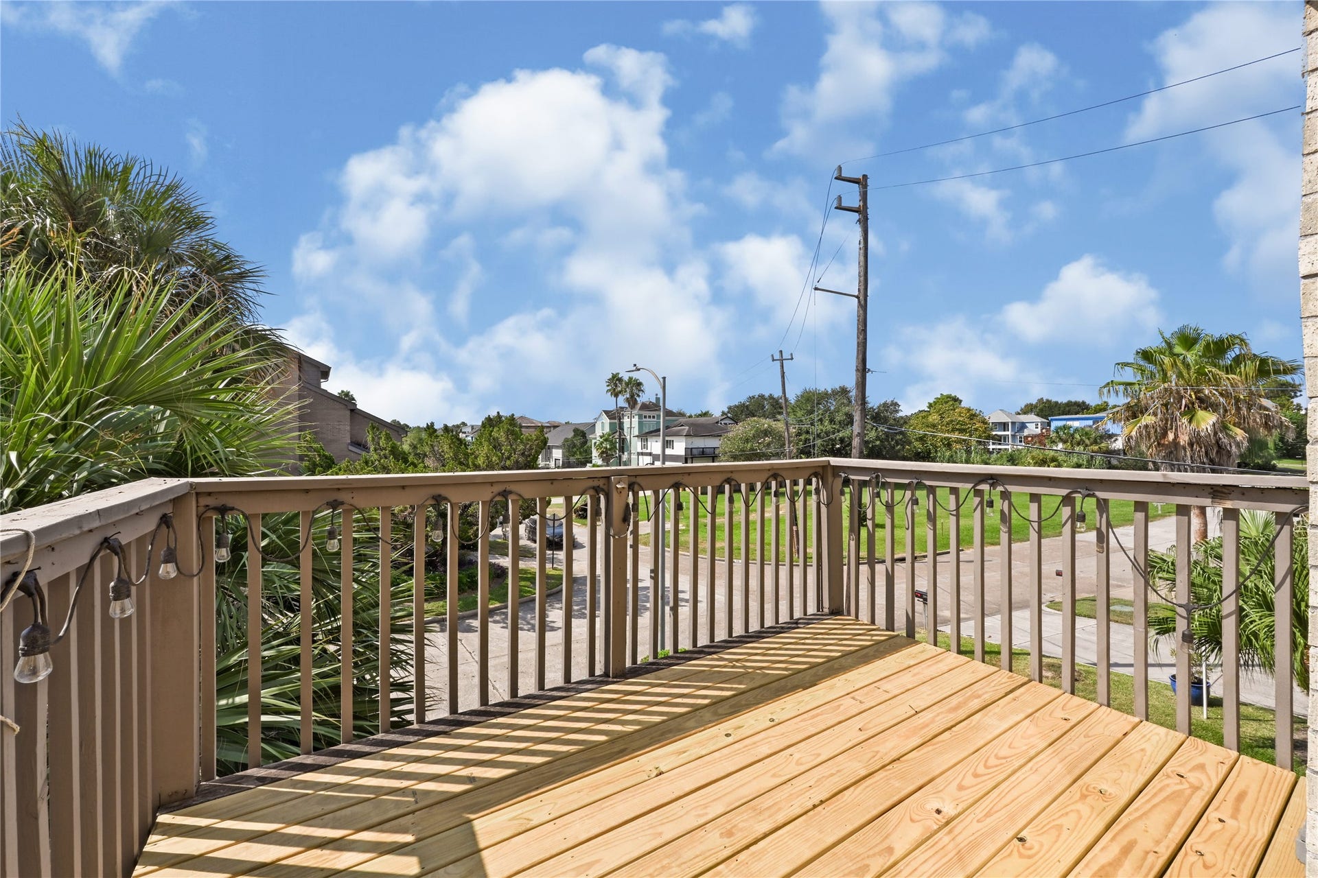 2607 Sailboat Drive, Houston, TX 77058 Enjoy serene views from this inviting wooden deck, perfect for relaxing and entertaining, surrounded by lush greenery and bright blue skies.