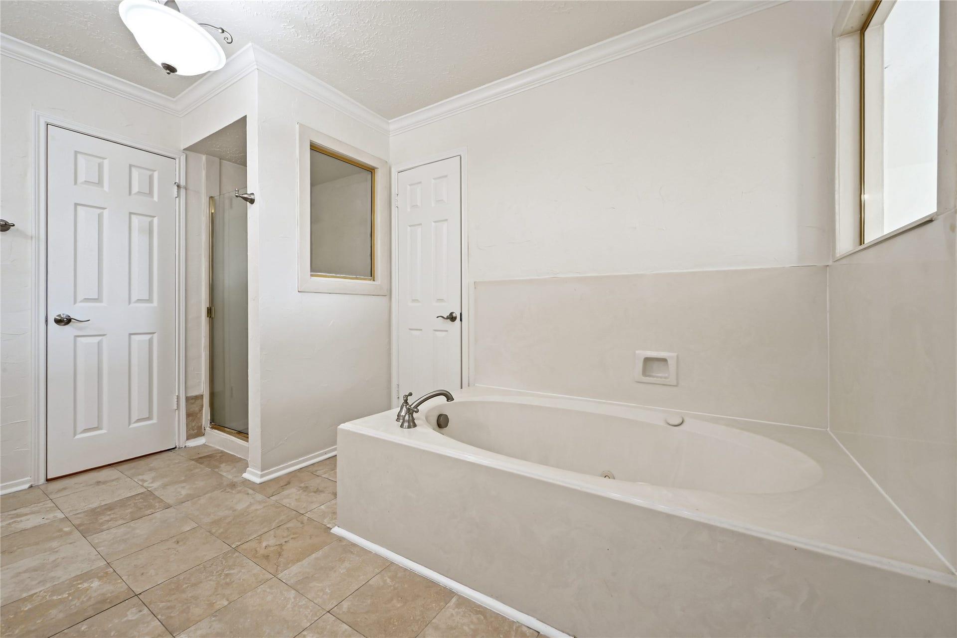 2607 Sailboat Drive, Houston, TX 77058 Spacious bathroom featuring a luxurious soaking tub, separate glass-enclosed shower, and elegant tile flooring, offering a serene retreat.