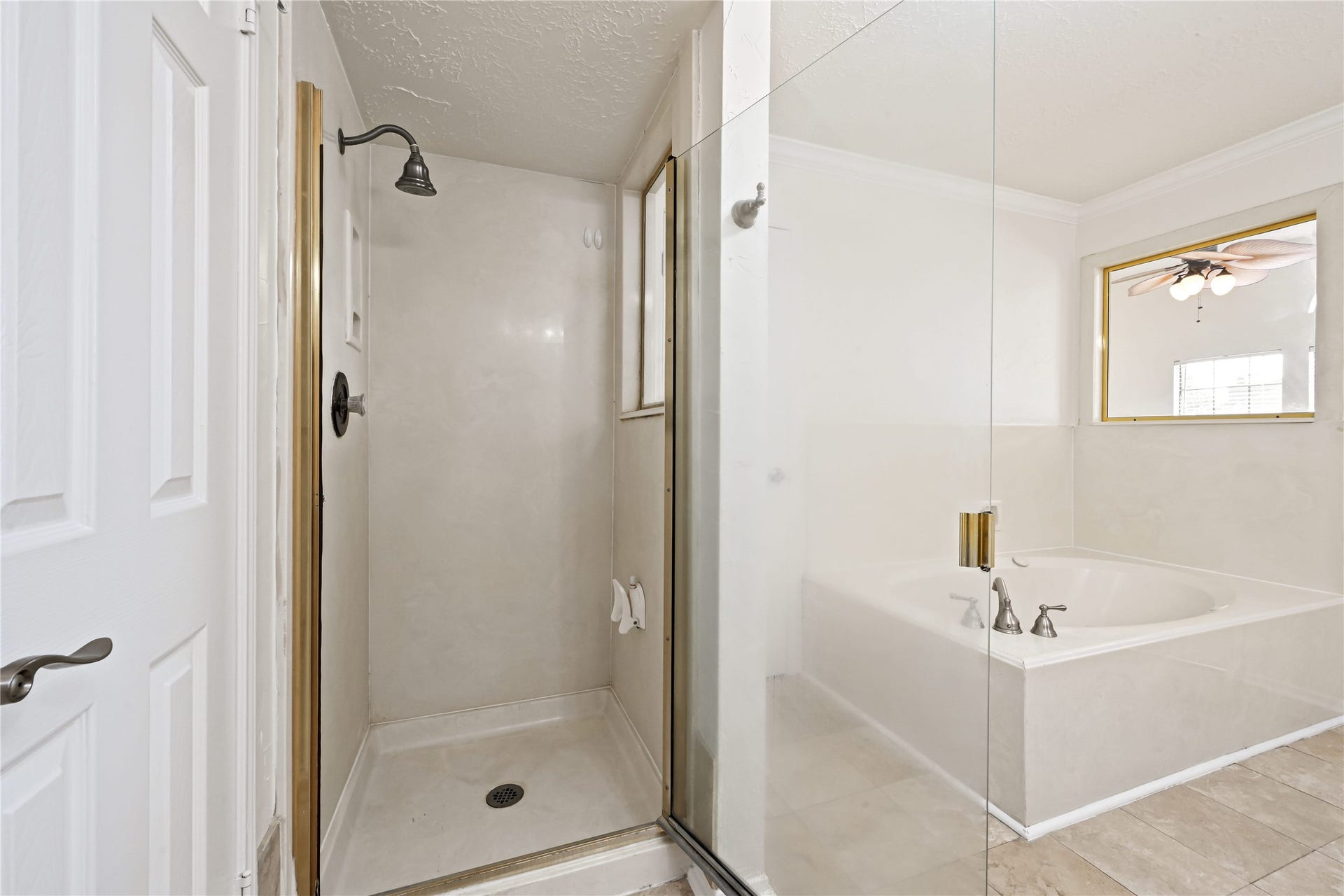 2607 Sailboat Drive, Houston, TX 77058 Bathroom features a glass-enclosed shower and a large soaking tub, offering a serene retreat with sleek fixtures and neutral tones.