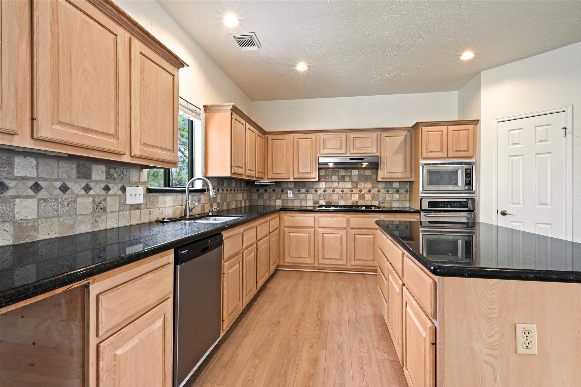 2607 Sailboat Drive, Houston, TX 77058 Kitchen features sleek black granite countertops, abundant light wood cabinetry, and modern stainless steel appliances, perfect for culinary enthusiasts.