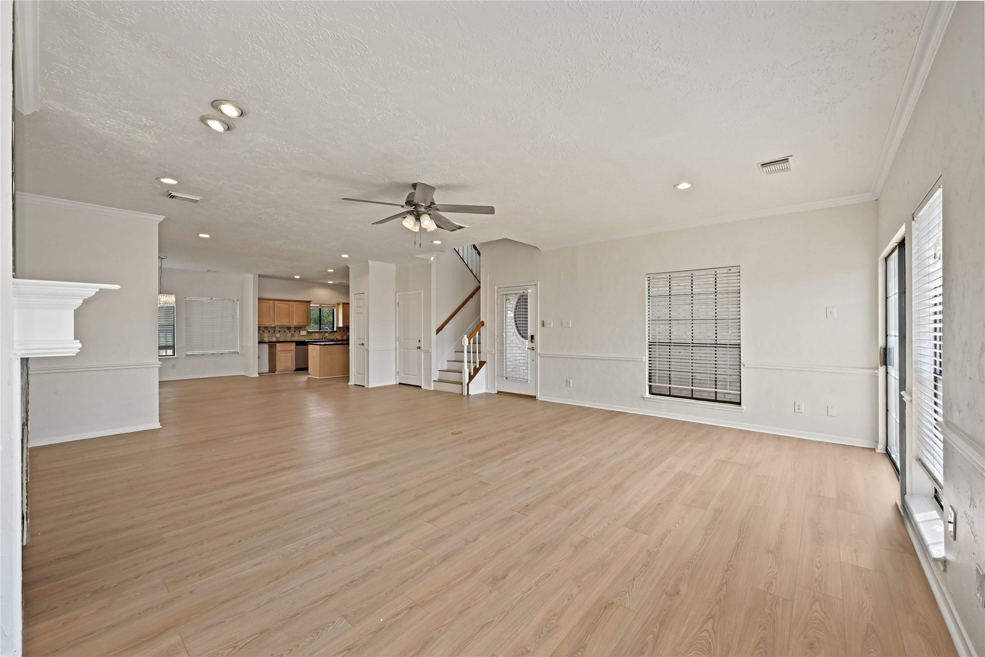 2607 Sailboat Drive, Houston, TX 77058 Lving area features elegant wood flooring, recessed lighting, and a ceiling fan, seamlessly connecting to a modern kitchen and featuring large windows for ample natural light.