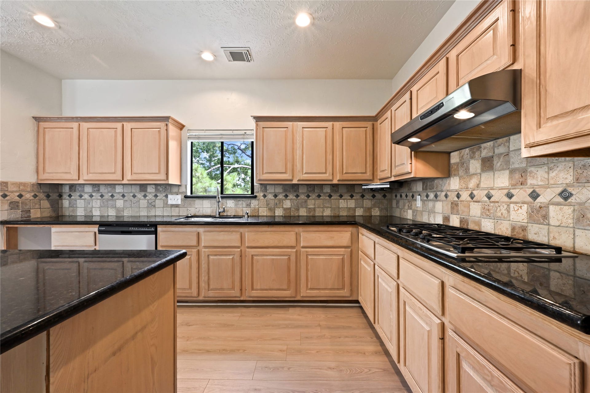 2607 Sailboat Drive, Houston, TX 77058 Spacious kitchen featuring natural wood cabinetry, sleek granite countertops, and a stylish tile backsplash.