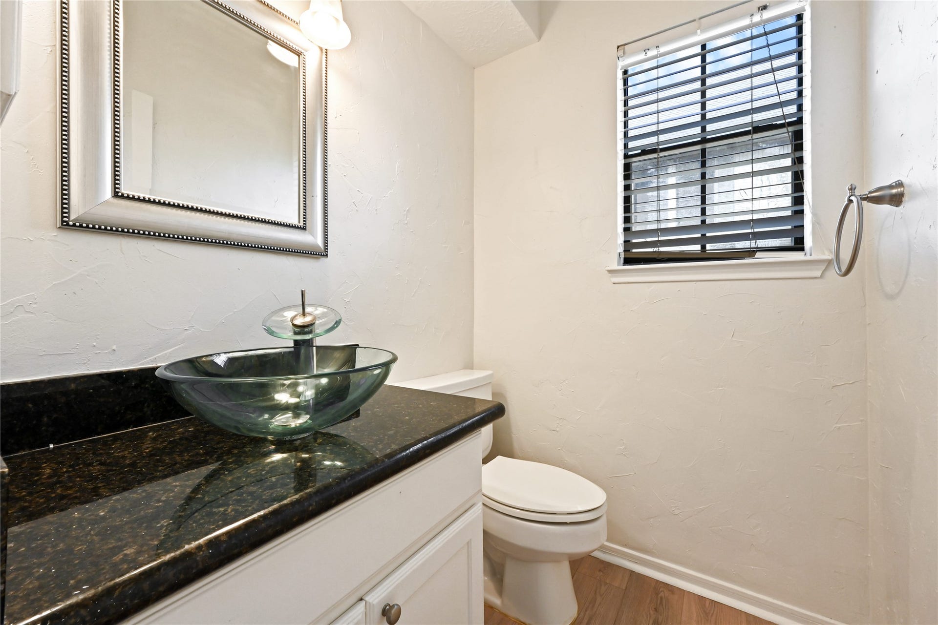 2607 Sailboat Drive, Houston, TX 77058 Chic powder room featuring a modern glass vessel sink, elegant black granite countertop, and soft natural light streaming through the window with stylish blinds.