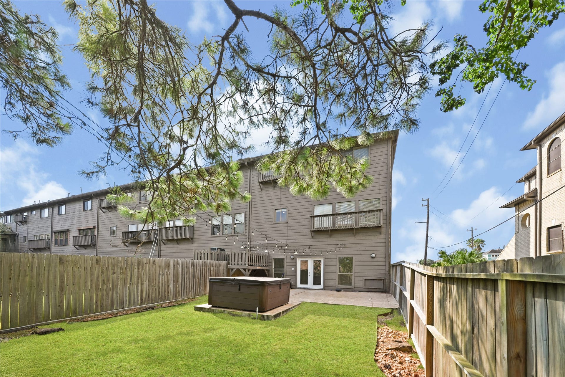 2607 Sailboat Drive, Houston, TX 77058 Expansive backyard with a patio and hot tub, enclosed by a wooden fence, perfect for outdoor relaxation and entertaining.
