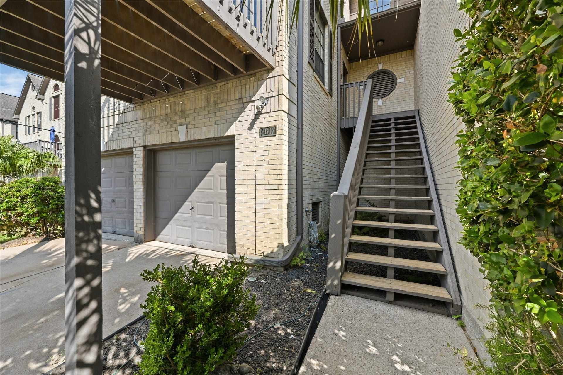2607 Sailboat Drive, Houston, TX 77058 Charming two-story home with a spacious two-car garage and inviting wooden staircase leading to the main entrance, surrounded by lush greenery.