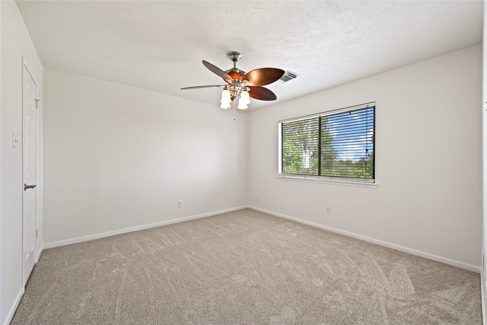2607 Sailboat Drive, Houston, TX 77058 Spacious bedroom with soft carpet flooring, a ceiling fan, and a large window providing abundant natural light.