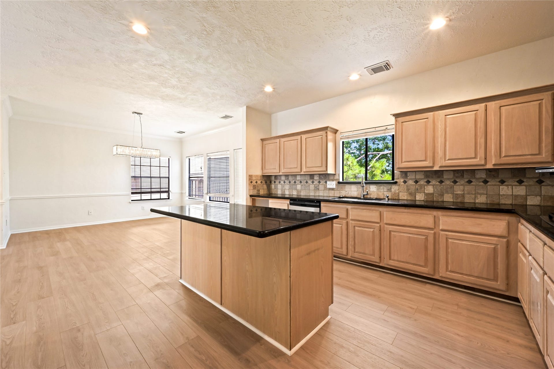 2607 Sailboat Drive, Houston, TX 77058 Spacious open-concept kitchen and dining area featuring sleek black countertops, ample cabinetry, and abundant natural light.