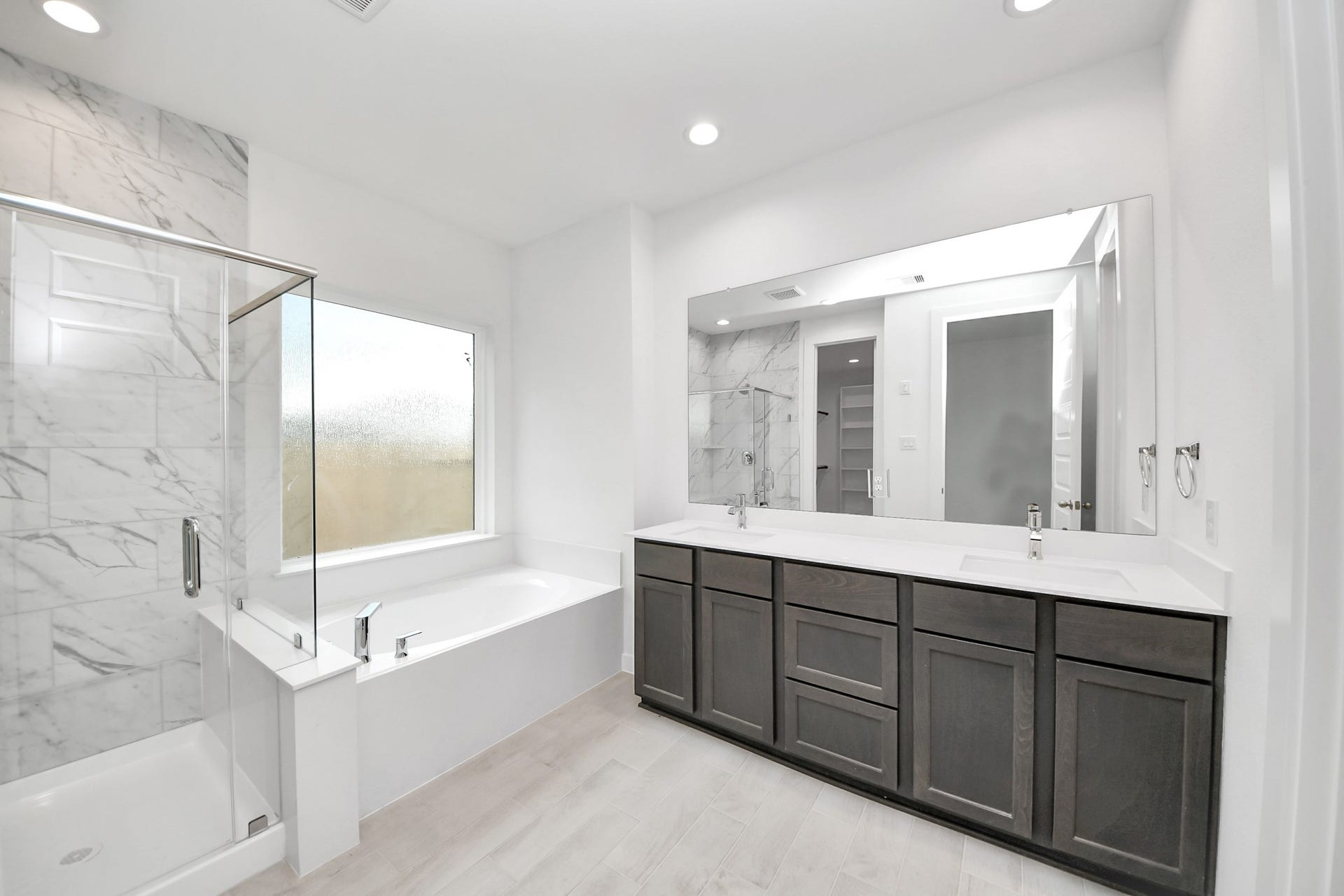 24515 Broad Park Ct, Spring, TX 77373 Escape to a spa-like oasis in this primary bathroom. Enjoy a walk-in shower with tile surround, a separate garden tub with custom detailing, and an elegant vanity featuring light countertops, modern hardware, and beautiful vanity lights. Experience luxury and relaxation in every detail.