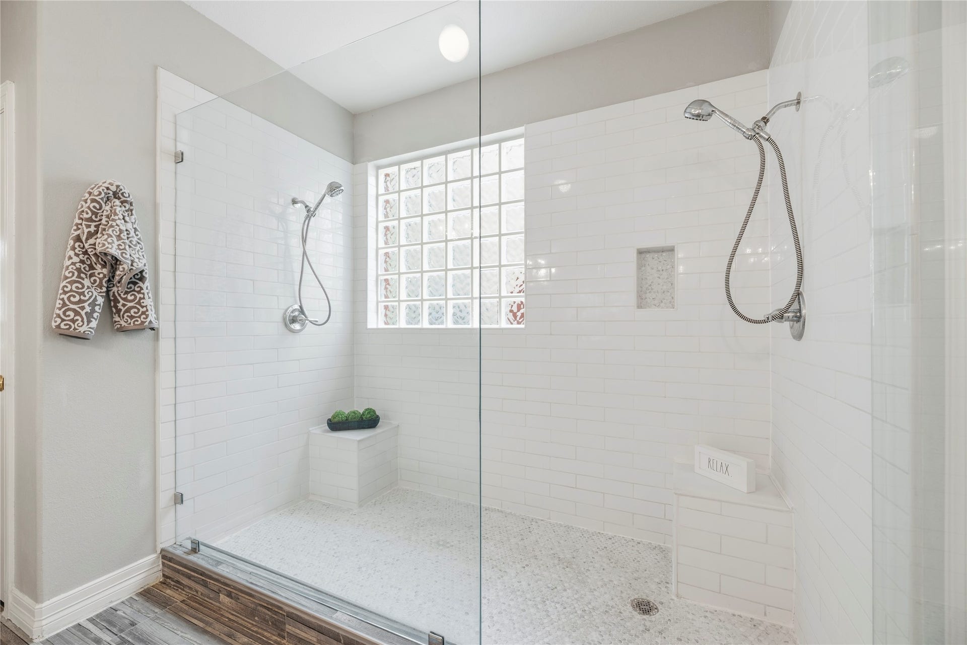 Oversized frame less shower with dual shower heads and benches.
