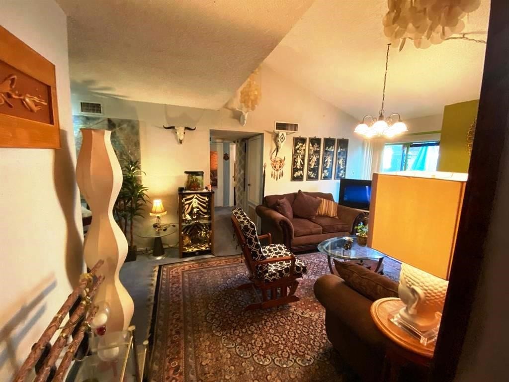 10049 Westpark Drive, #136, Houston, TX 77042 Cozy living room with warm lighting and eclectic decor. Features comfortable seating, a glass coffee table, and decorative wall art. The space has a welcoming ambiance with a mix of modern and rustic elements, perfect for relaxation.