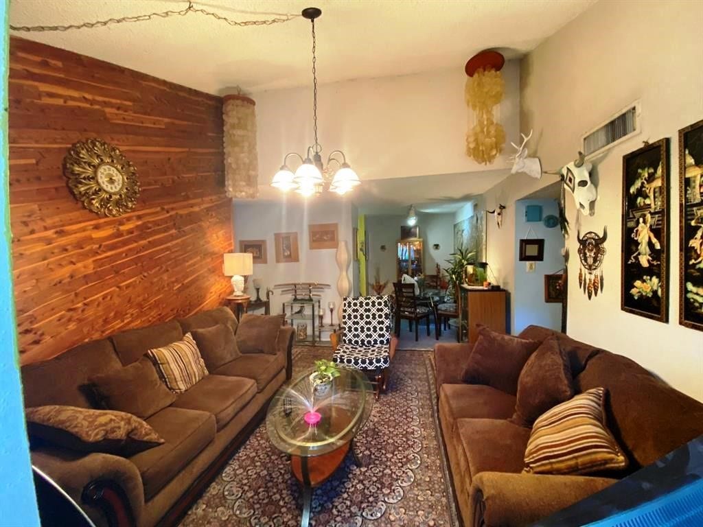 10049 Westpark Drive, #136, Houston, TX 77042 Cozy living room with warm wood accents, plush brown sofas, and eclectic decor. Features a unique wood-paneled wall, ambient lighting, and an inviting atmosphere. Perfect for relaxation and entertaining.