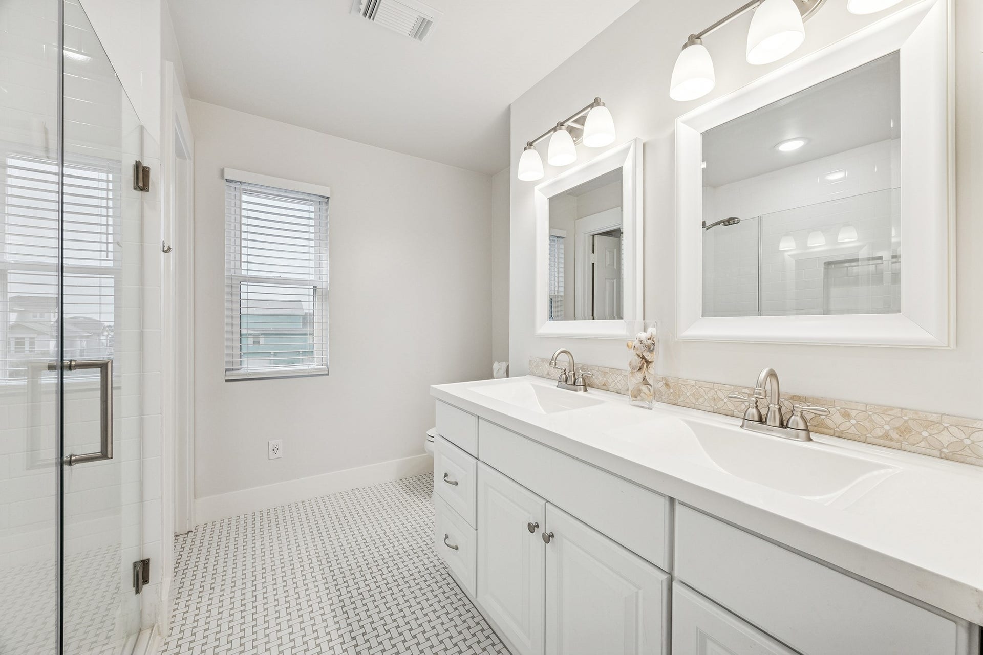 1814 Tiki Drive, Tiki Island, TX 77554 Experience luxury in this pristine primary bath, featuring a spacious double vanity, elegant lighting, and a sleek glass shower, perfect for unwinding in style.