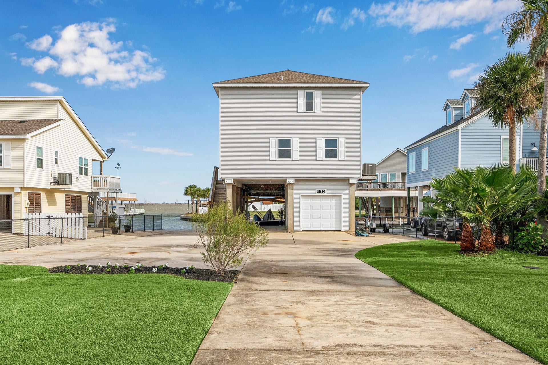 1814 Tiki Drive, Tiki Island, TX 77554 Nestled by the water, this charming three-story home boasts a spacious driveway, lush greenery, and a welcoming facade, offering picturesque waterfront living.