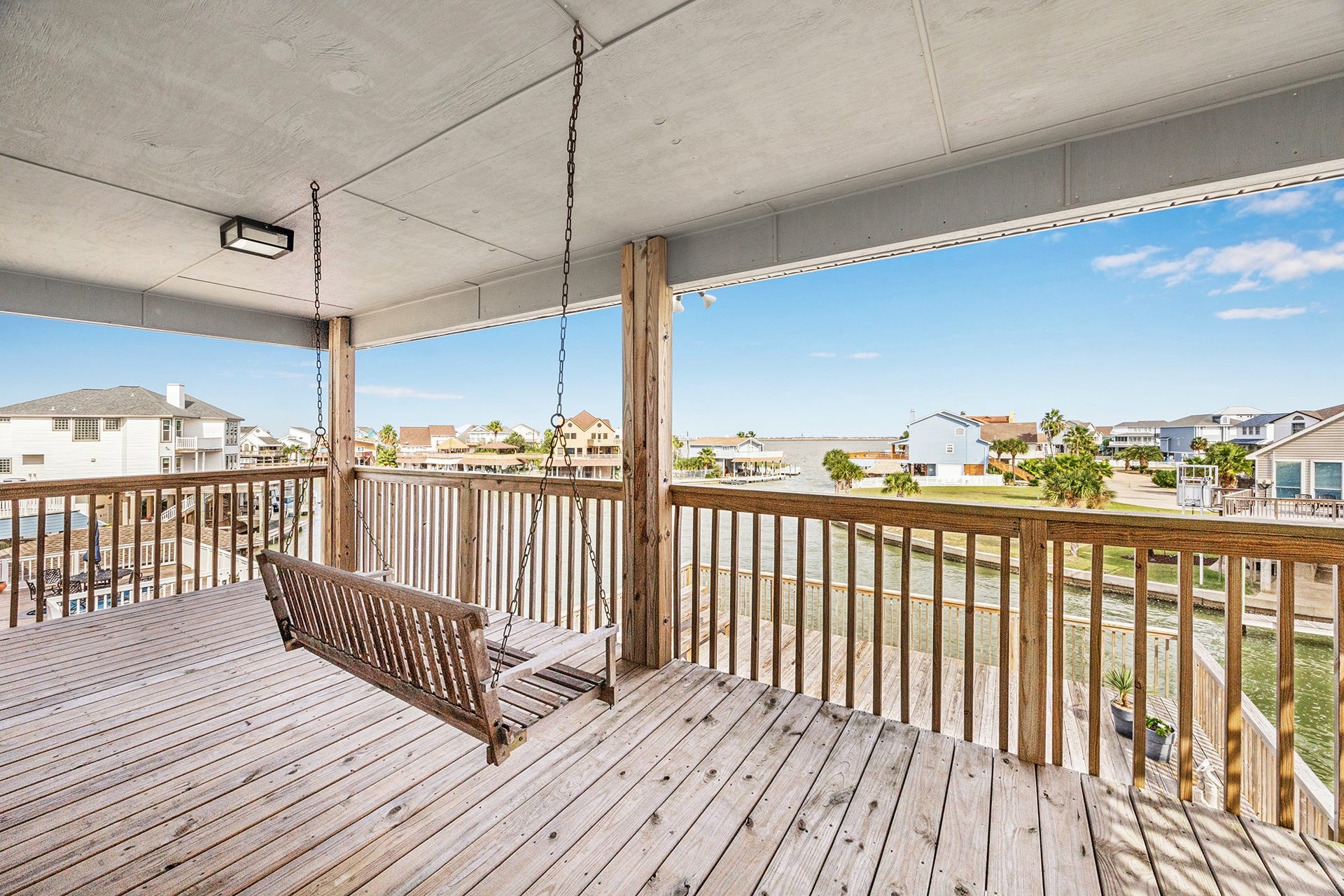 1814 Tiki Drive, Tiki Island, TX 77554 Enjoy serene waterfront views from this spacious outside deck, complete with a charming swing perfect for relaxing afternoons.