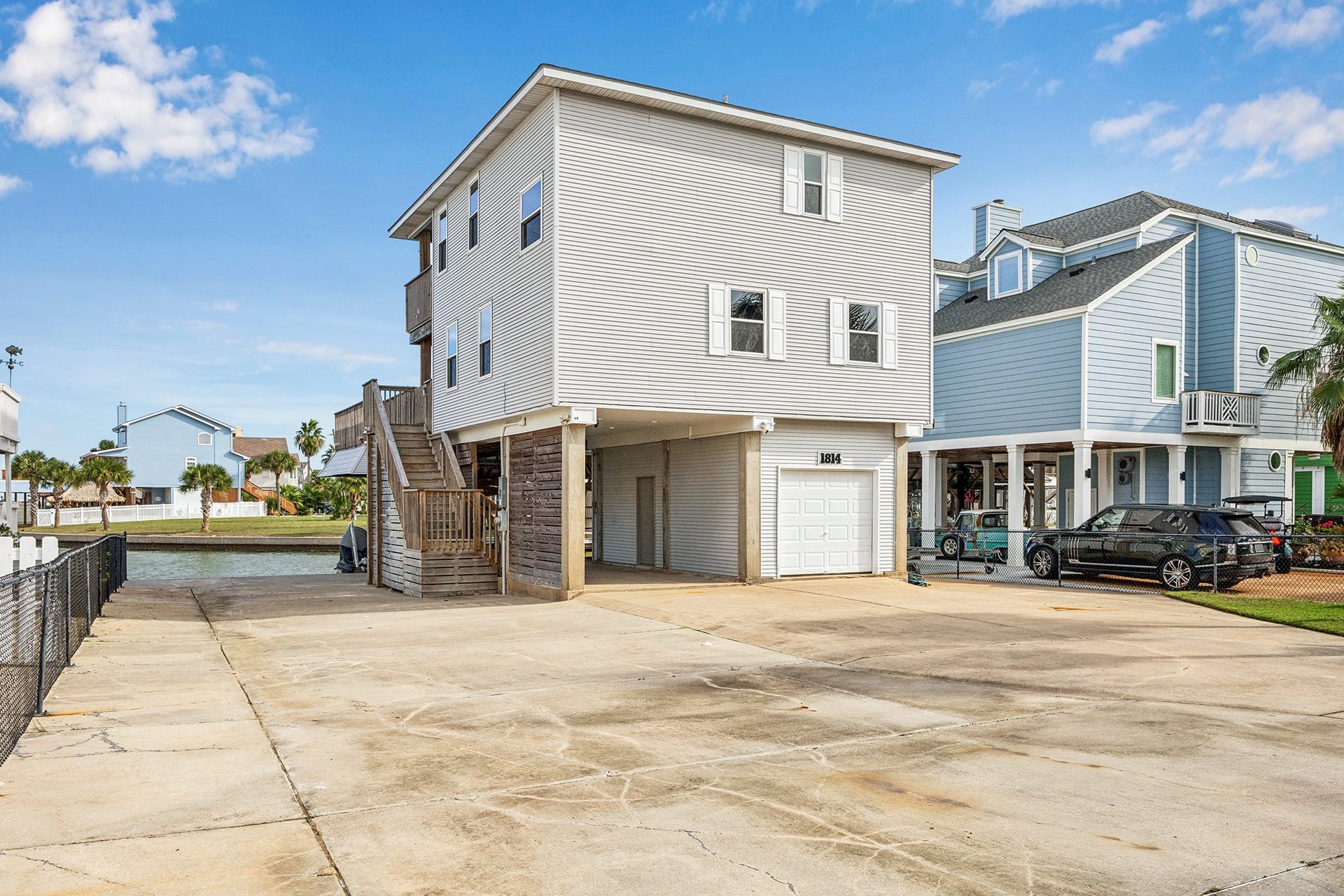 1814 Tiki Drive, Tiki Island, TX 77554 This inviting home boasts a welcoming facade and ample parking space, perfect for accommodating family and friends with ease.