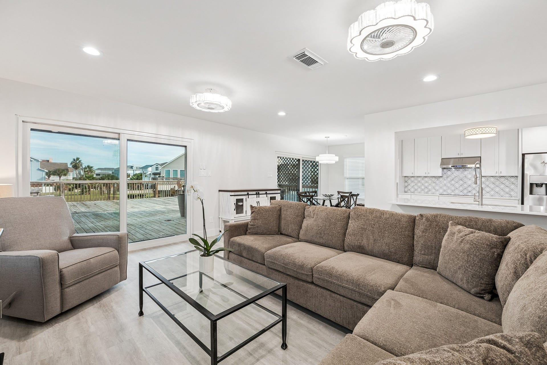1814 Tiki Drive, Tiki Island, TX 77554 Experience serene living with this open-concept space, featuring neutral tones that seamlessly blend a cozy living area, modern kitchen, and expansive deck views.