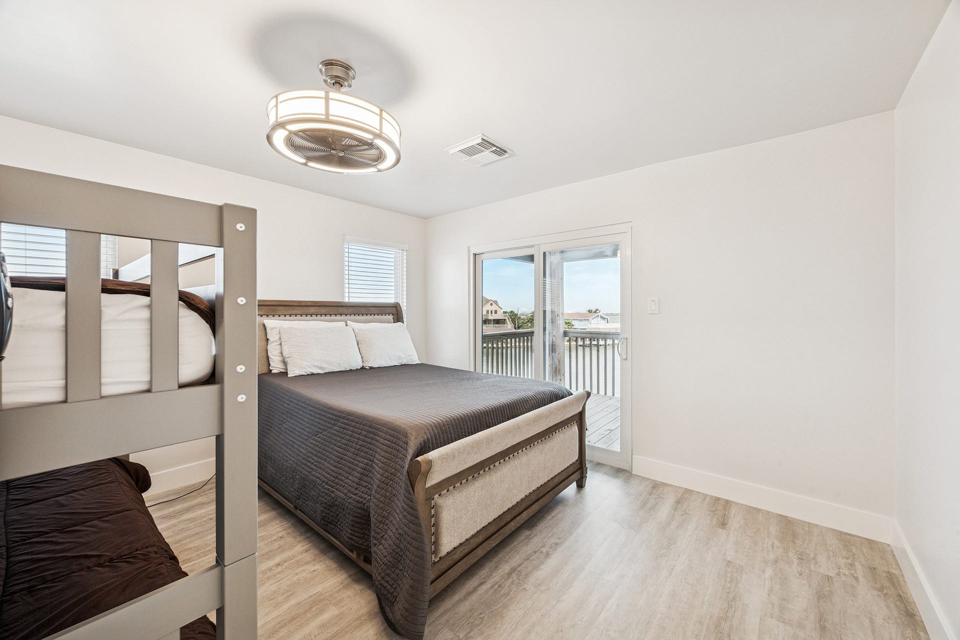 1814 Tiki Drive, Tiki Island, TX 77554 Discover a bright, inviting bedroom featuring sleek flooring, a cozy bed, and glass doors opening to serene water viewsyour perfect retreat.
