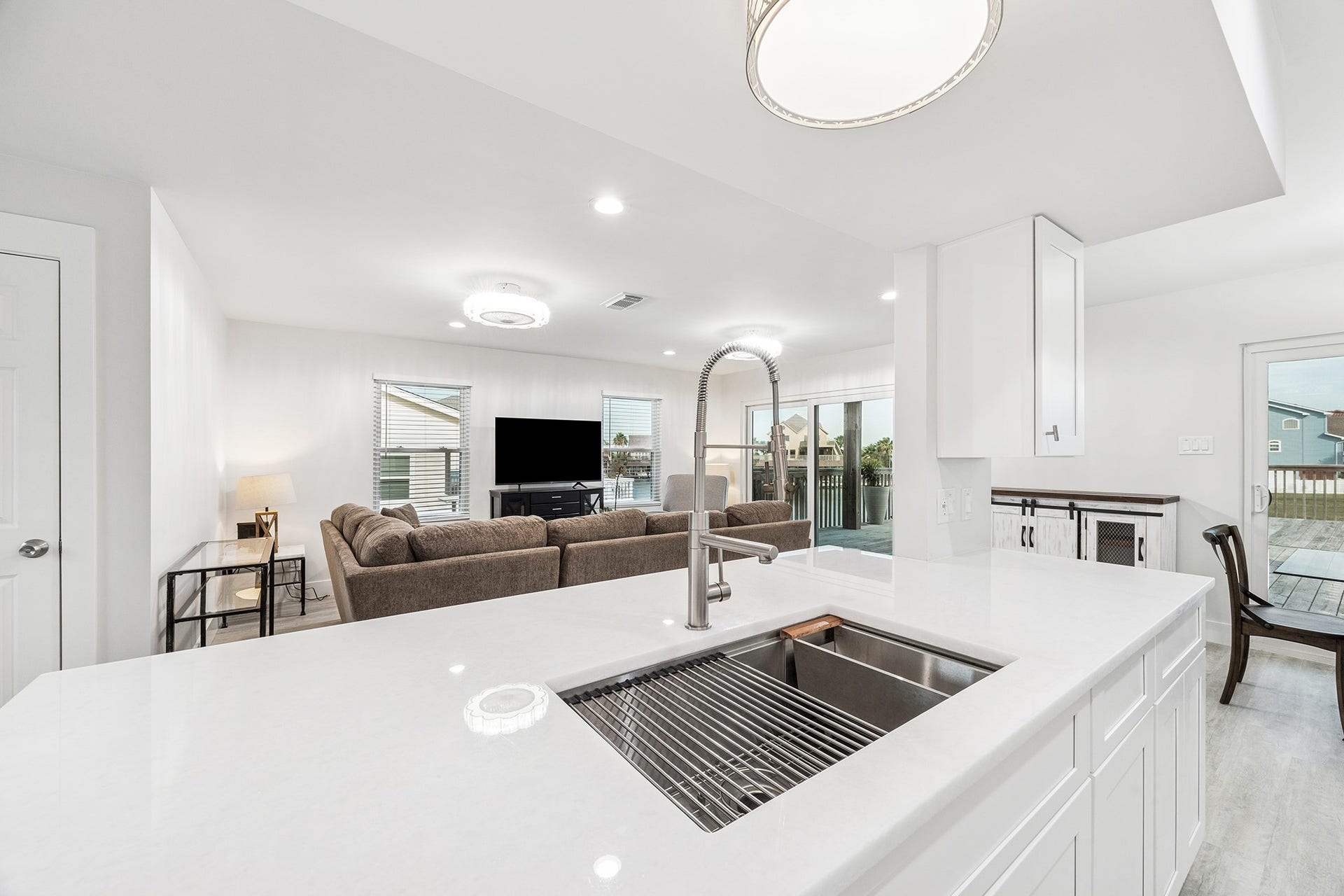 1814 Tiki Drive, Tiki Island, TX 77554 Discover a bright, open-concept living space where a sleek kitchen island with a modern sink seamlessly connects to a cozy living area, perfect for entertaining and enjoying natural light.