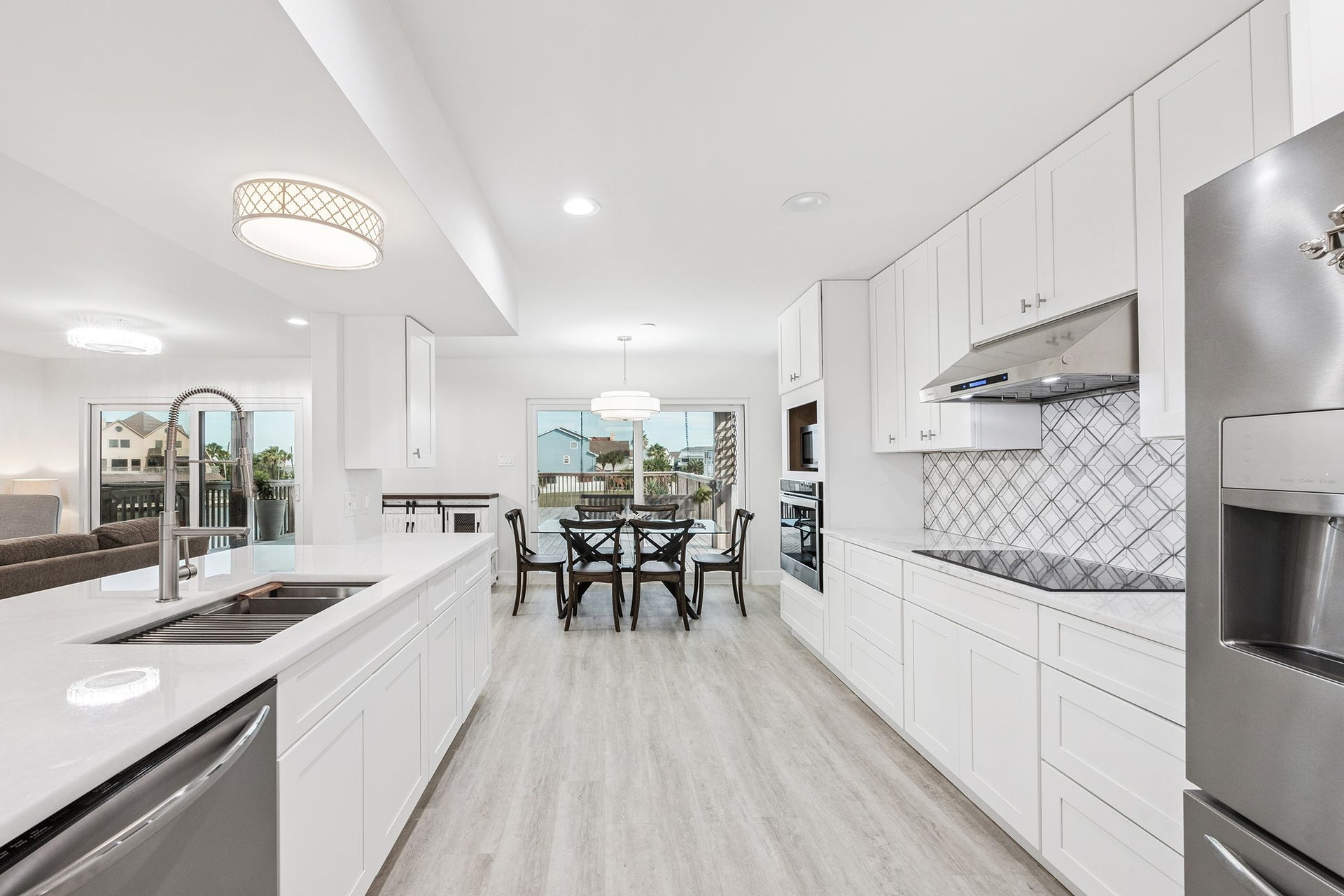 1814 Tiki Drive, Tiki Island, TX 77554 This kitchen offers a bright, modern space with sleek white cabinetry, stainless steel appliances, and an inviting open layout perfect for entertaining and family gatherings.
