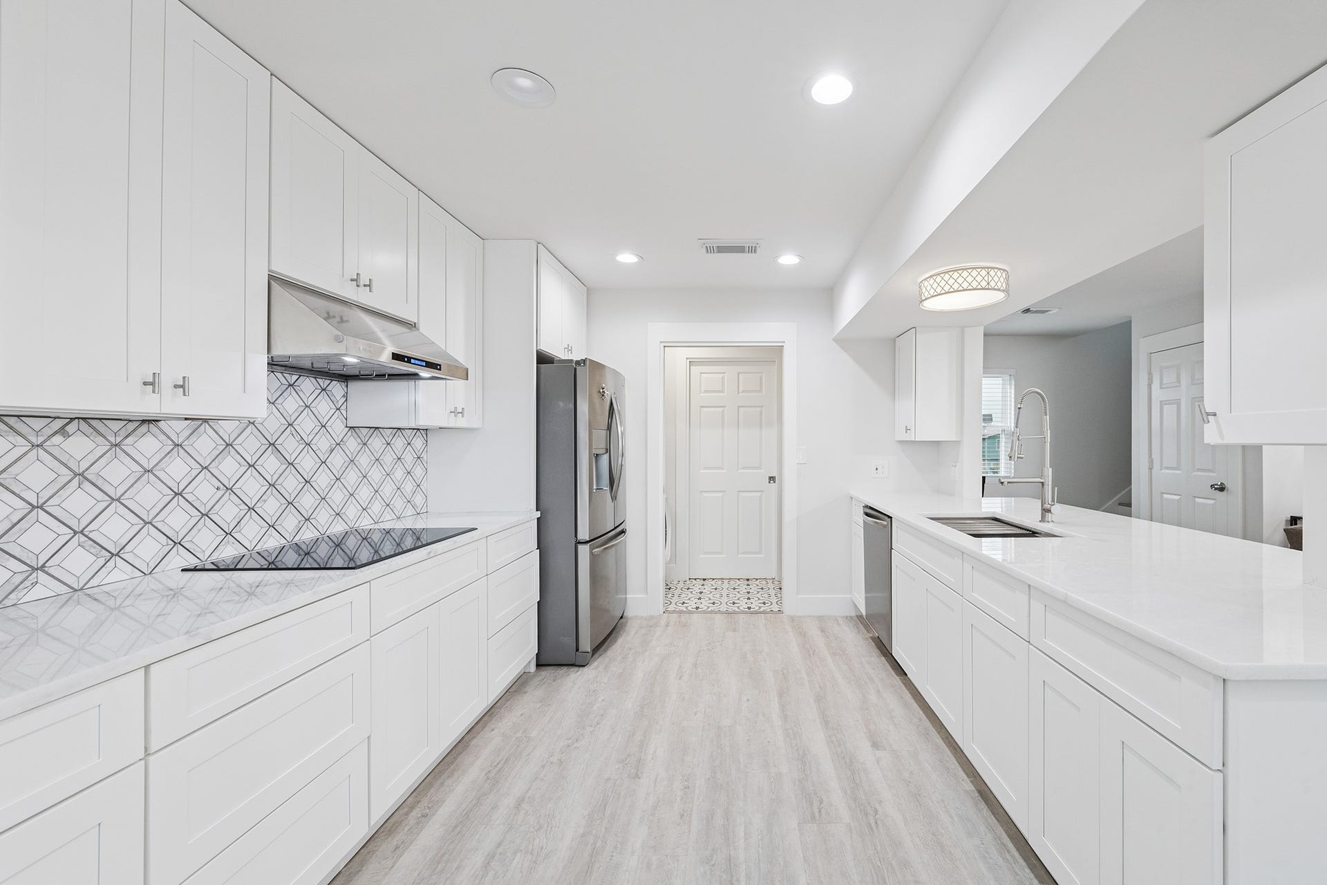 1814 Tiki Drive, Tiki Island, TX 77554 Discover culinary bliss in this sleek, modern kitchen featuring elegant white cabinetry, a chic geometric backsplash, and top-notch stainless steel appliances, all bathed in natural light.