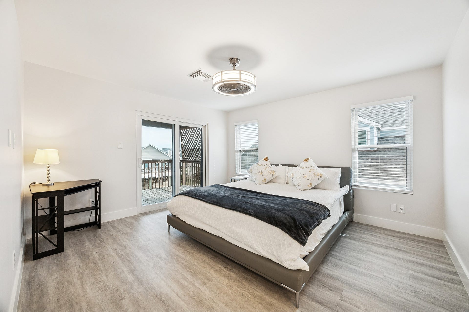 1814 Tiki Drive, Tiki Island, TX 77554 Discover your serene retreat in this bright and airy primary bedroom, featuring sleek flooring, a modern light fixture, and sliding doors that open to a private deck for seamless indoor-outdoor living.