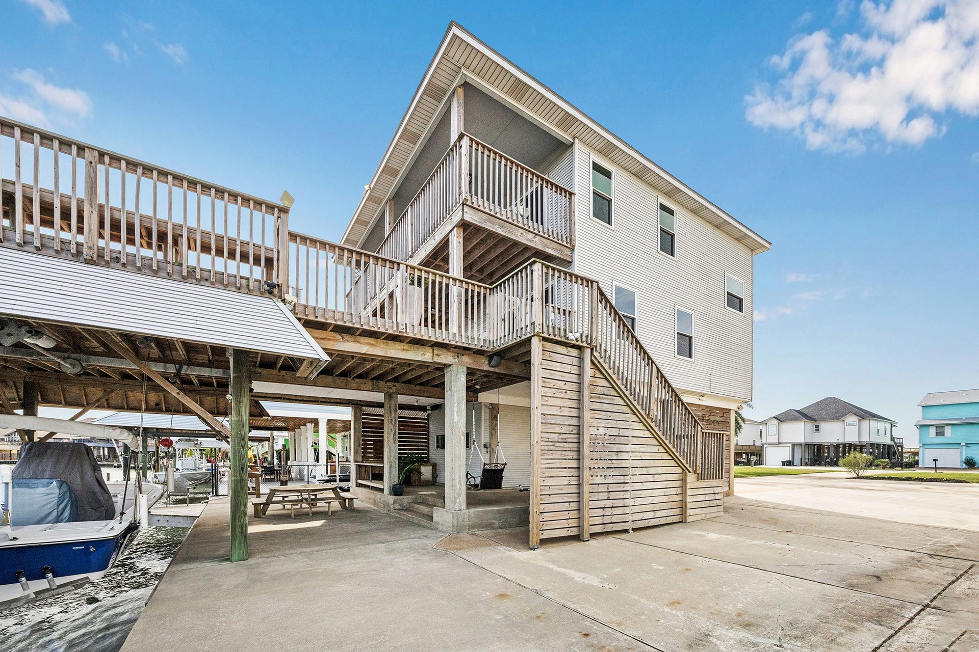 1814 Tiki Drive, Tiki Island, TX 77554 This stunning coastal home features an inviting side with expansive decking, perfect for enjoying waterfront views and outdoor living, complete with a spacious covered area for relaxation and entertainment.