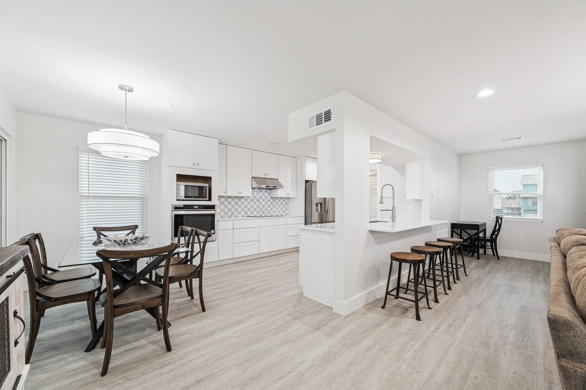 1814 Tiki Drive, Tiki Island, TX 77554 This bright and modern kitchen-dining area features sleek white cabinetry, a spacious breakfast bar with seating, and an inviting dining space perfect for entertaining.