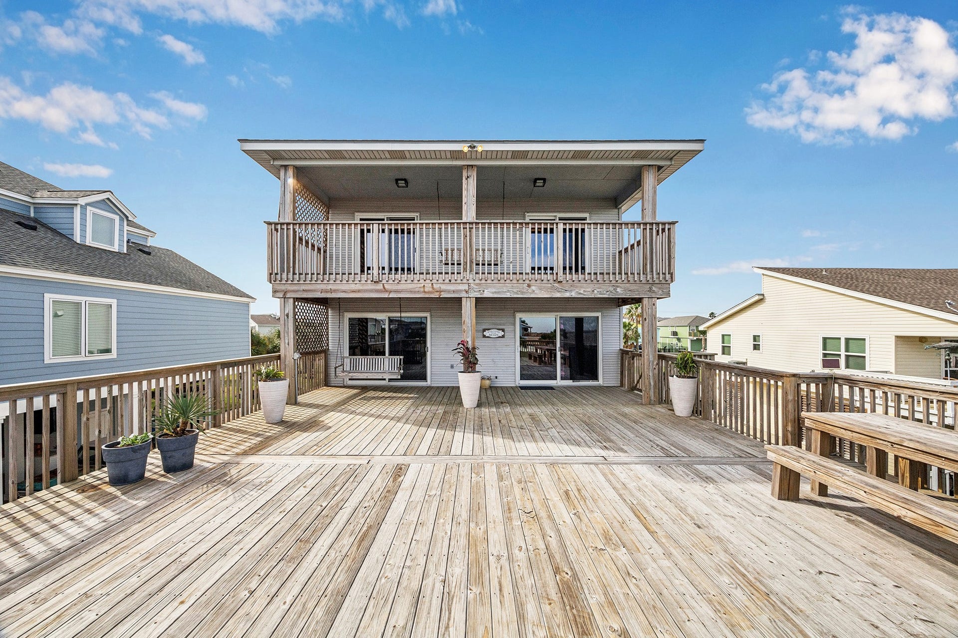 1814 Tiki Drive, Tiki Island, TX 77554 Explore the perfect blend of relaxation and entertainment with this home's expansive, sunlit deck and charming upper balcony, ideal for enjoying serene views and hosting memorable gatherings.