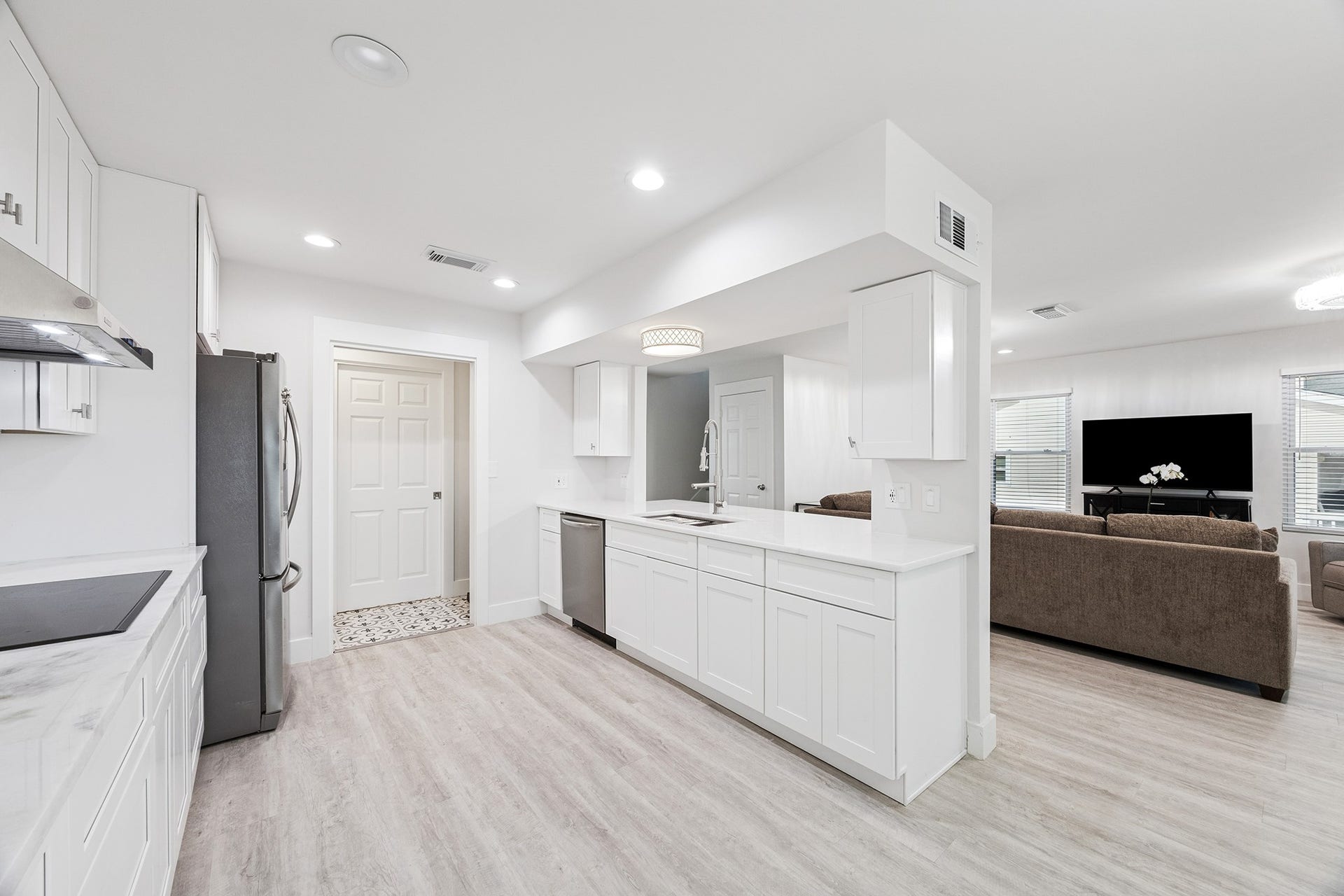 1814 Tiki Drive, Tiki Island, TX 77554 This bright, modern kitchen features sleek white cabinetry, stainless steel appliances, and an open layout that seamlessly connects to a cozy living areaperfect for entertaining and everyday living.