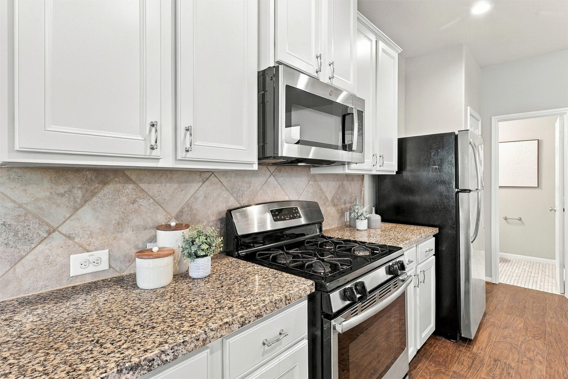 8323 Lamond Lane, Houston, TX 77095 The solid wood cabinets feature a delicate bevel on the drawer and door fronts. The tile backsplash, granite counters, paint, nickel finishes, and stainless steel appliances create a cohesive palette.