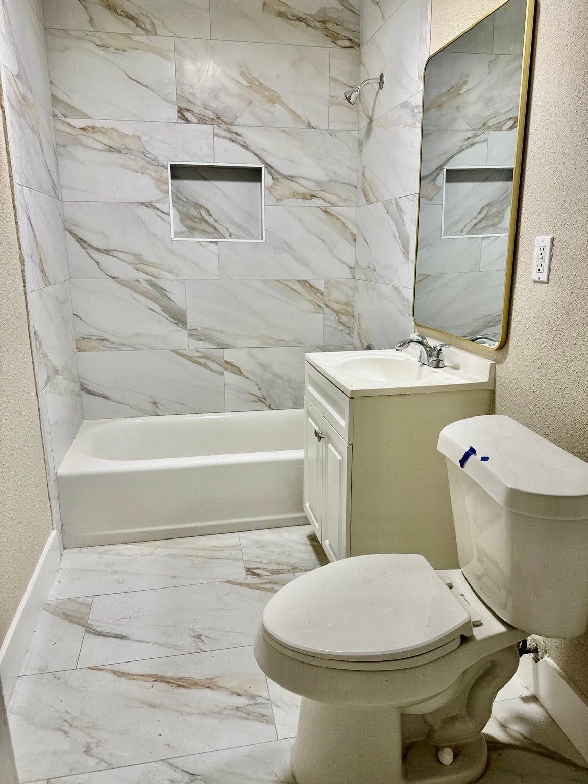 Elegant bathroom featuring modern marble tilework, a sleek vanity, and a spacious tub-shower combo.