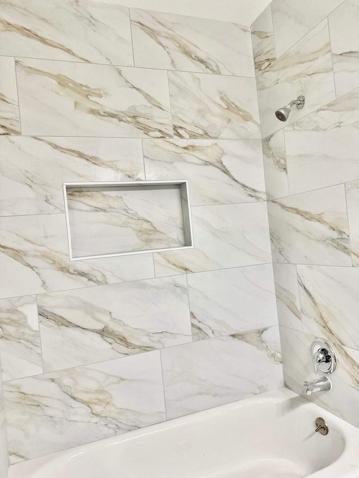 Elegant bathroom featuring a luxurious marble-tiled shower with a built-in niche and modern chrome fixtures.