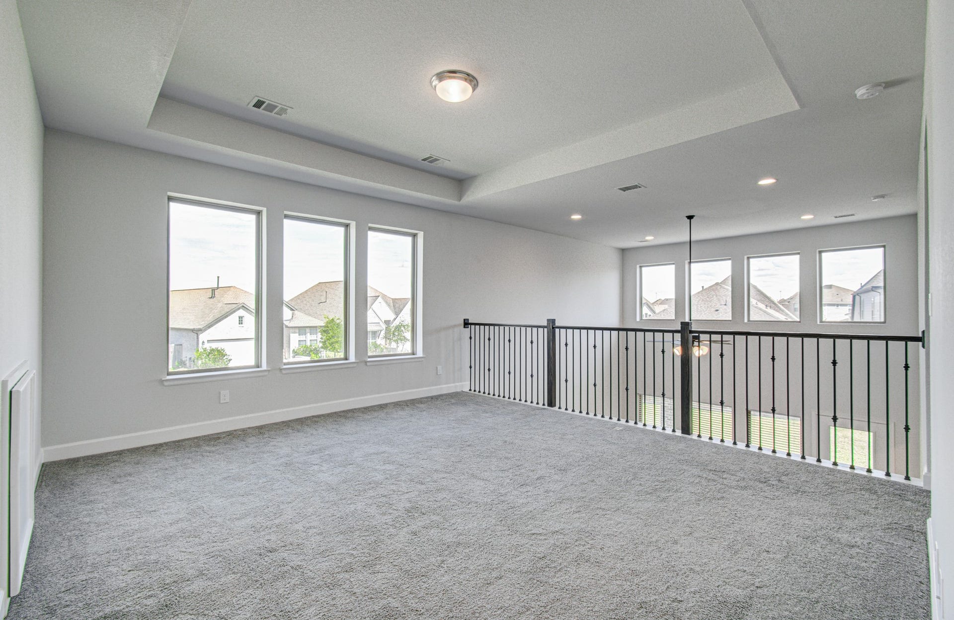 Spacious and bright loft gameroom area with large windows, elegant railing, and recessed lighting, perfect for a versatile living space.