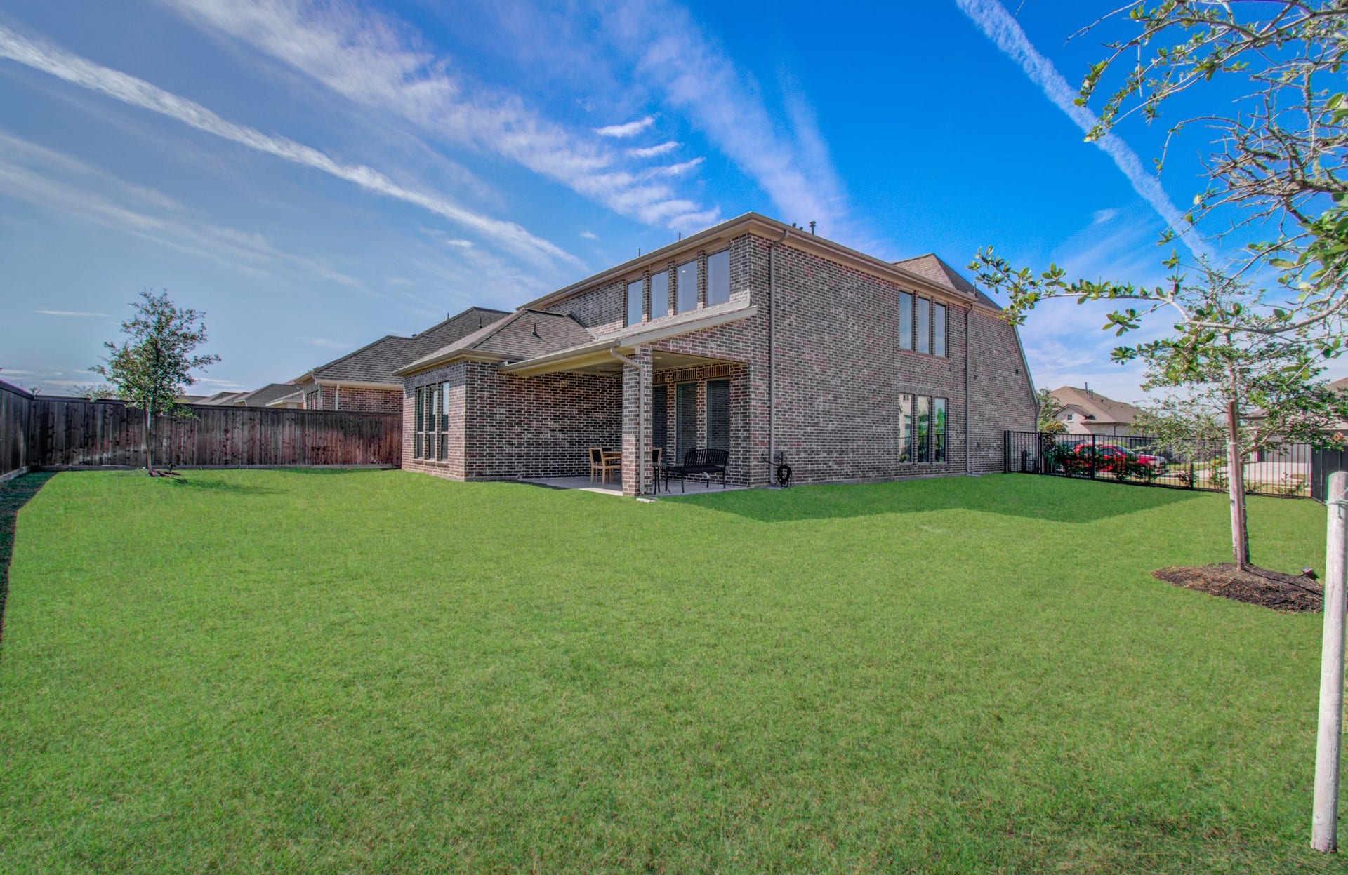 Spacious backyard with lush green lawn and covered patio, perfect for outdoor relaxation and entertaining.