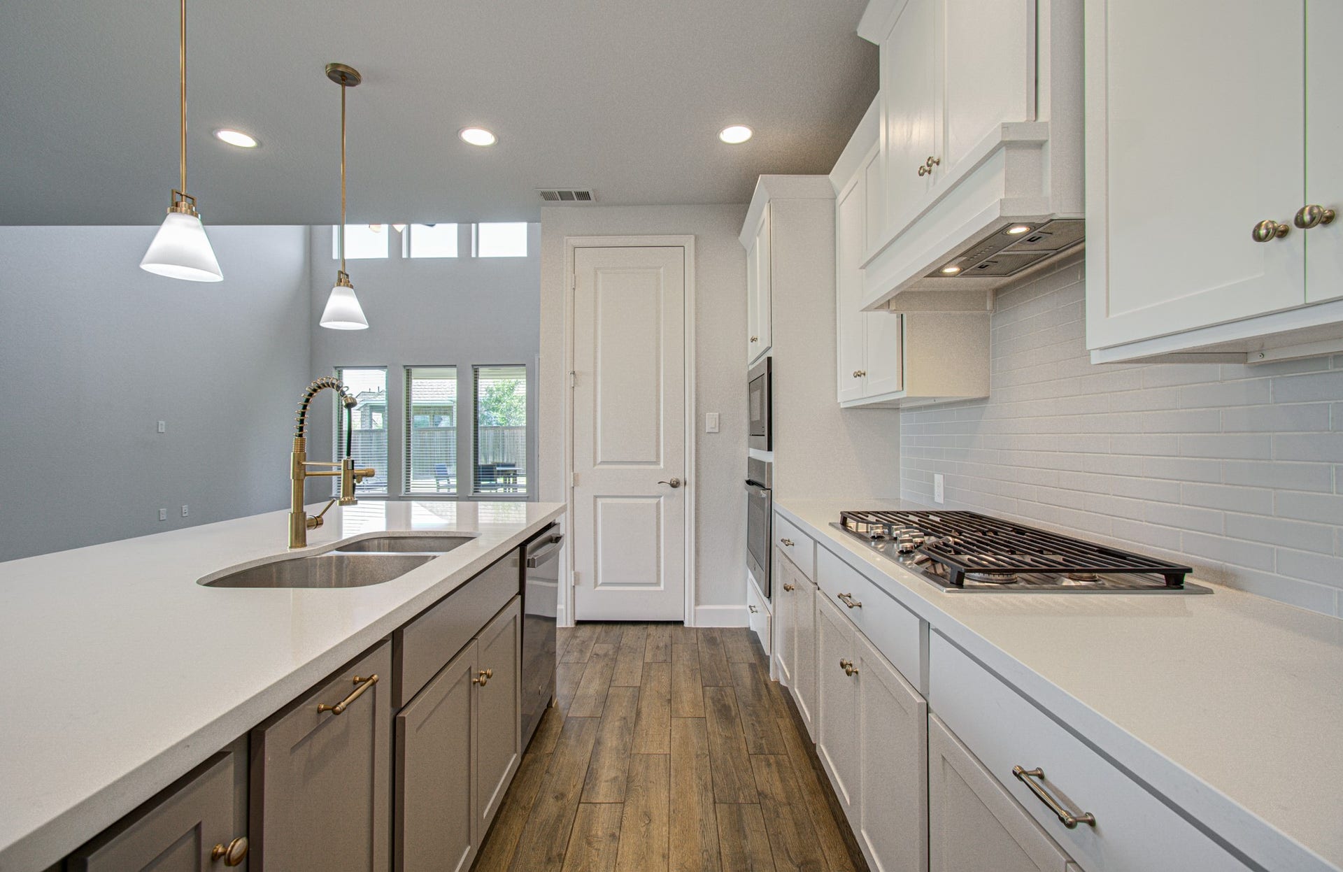 Modern kitchen featuring sleek white cabinetry, stainless steel appliances, and a spacious island with elegant pendant lighting.