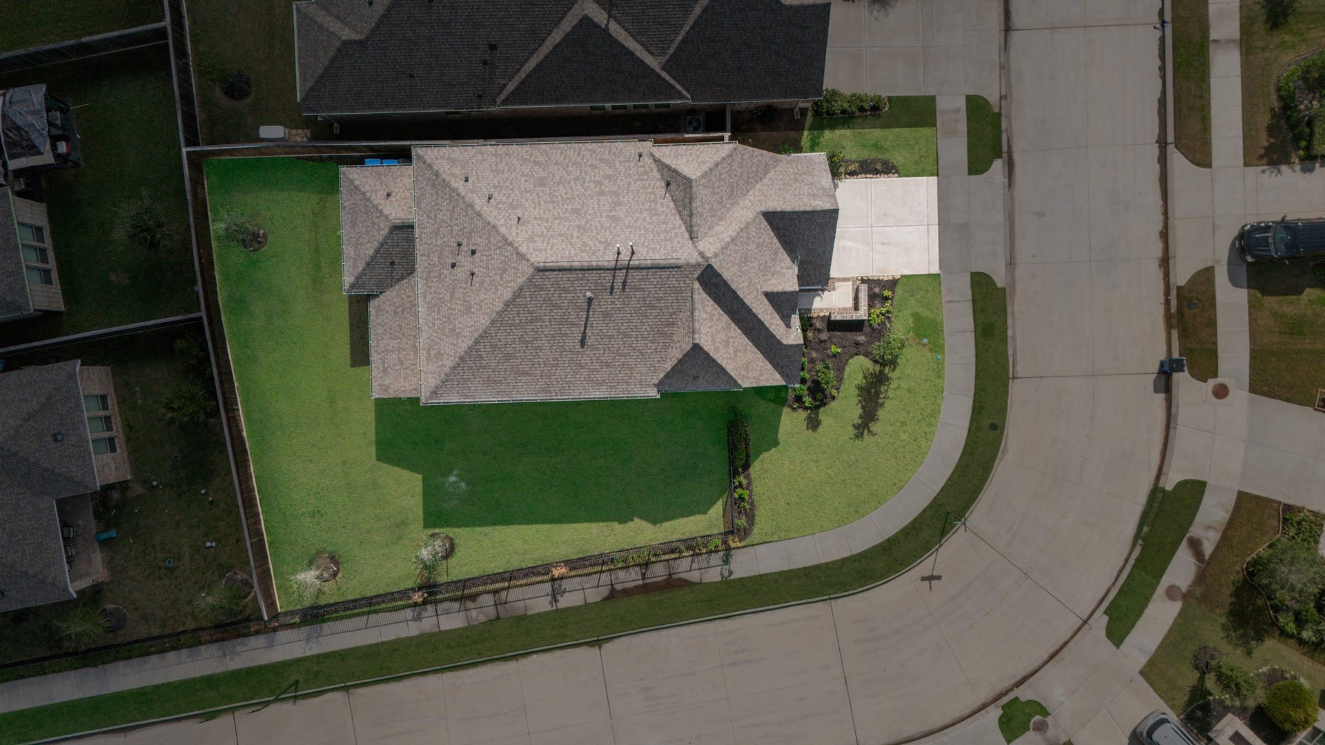 Spacious corner-lot home with a well-maintained lawn, ample driveway, and privacy fencing.