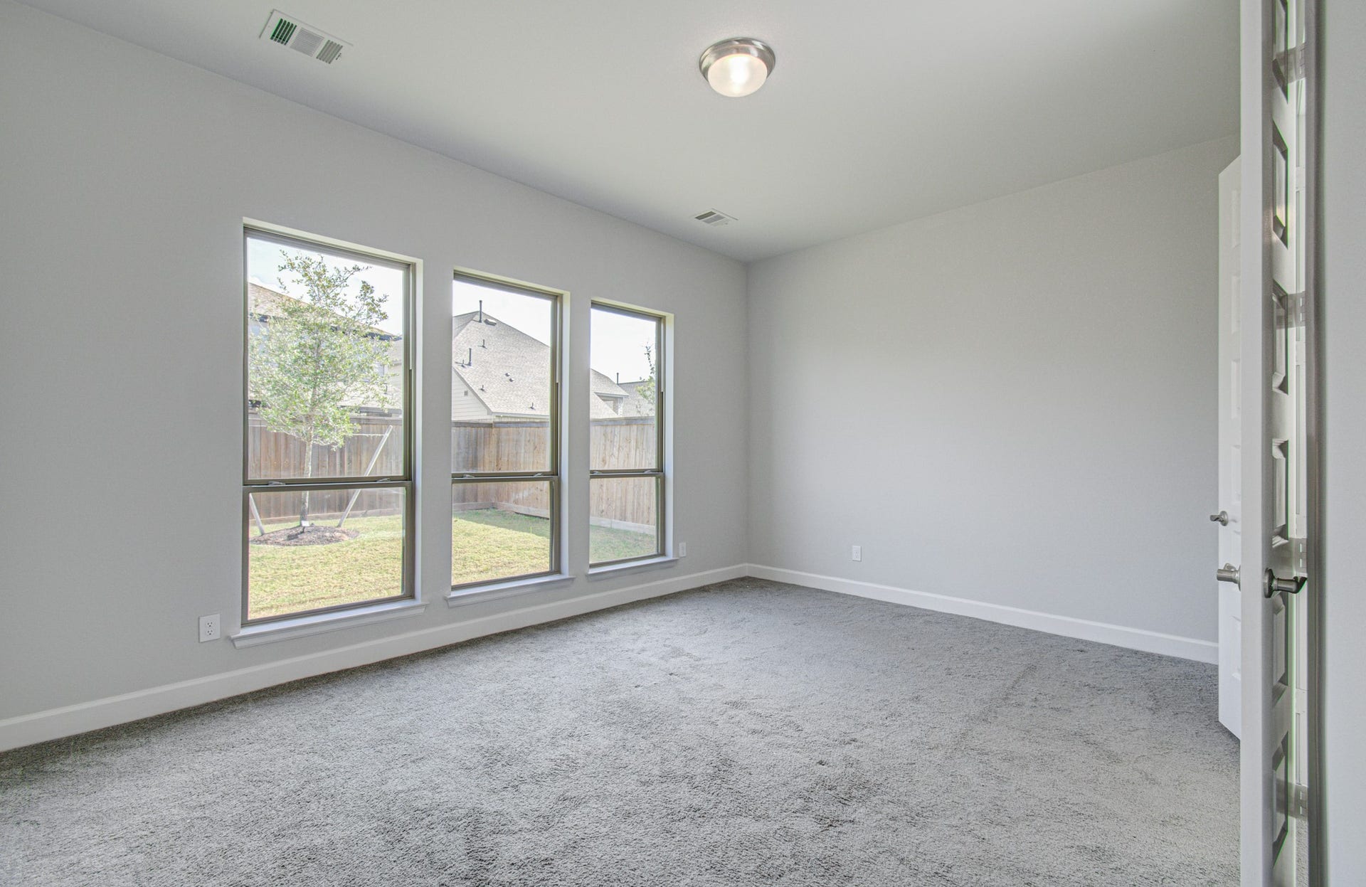 Bright and airy primary bedroom featuring tall ceilings and large windows overlooking the backyard.