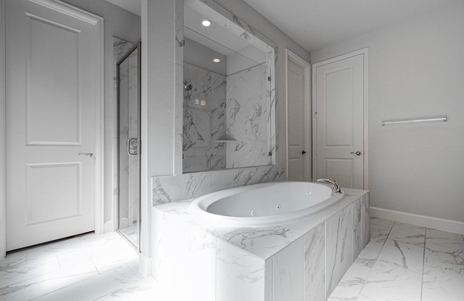 Spa-like jetted tub and elegant tile finishes, complemented by a glass-enclosed shower for a serene retreat.