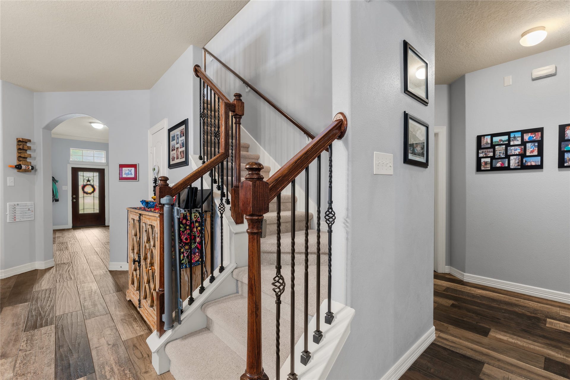 20184 Bitter Root Drive, Porter, TX 77365 Inviting entryway with elegant wood and wrought iron staircase, complemented by warm wood flooring and soft gray walls.