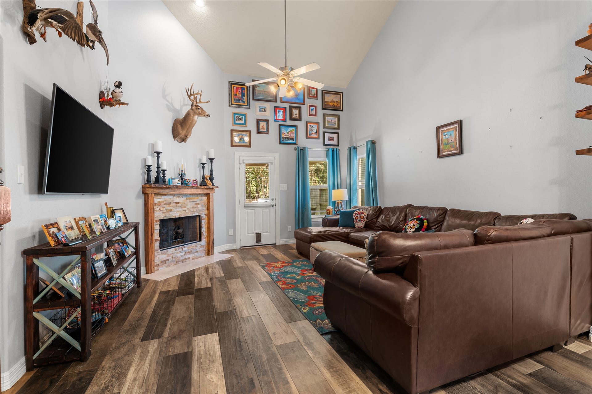 20184 Bitter Root Drive, Porter, TX 77365 Spacious living room with vaulted ceilings, a cozy brick fireplace, and a large sectional sofa. Abundant natural light and stylish decor create a warm and inviting atmosphere.