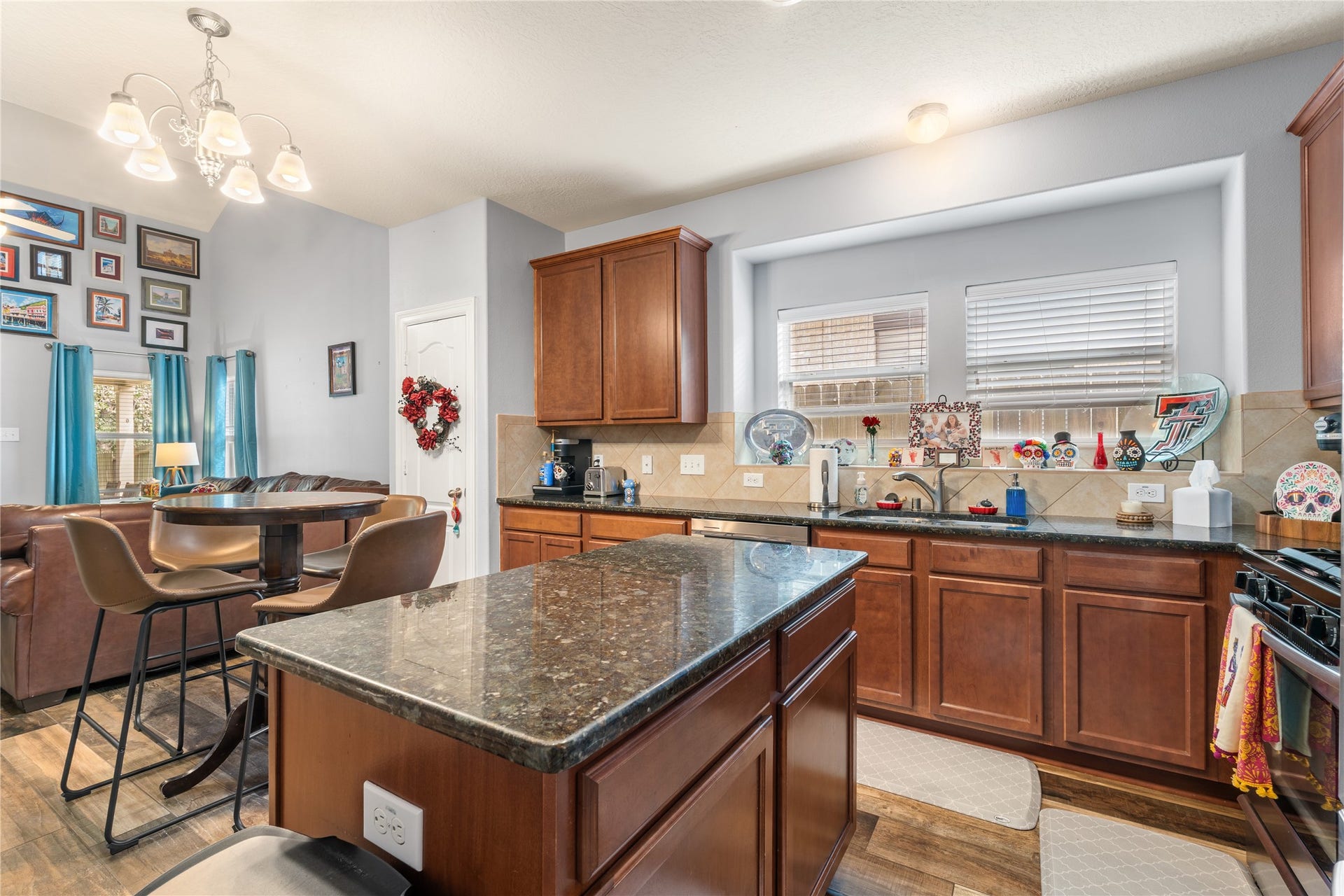 20184 Bitter Root Drive, Porter, TX 77365 Spacious kitchen with rich wooden cabinetry and granite countertops, featuring a central island and a cozy dining nook with stylish bar seating. Natural light pours in through large windows, creating a warm and inviting atmosphere.