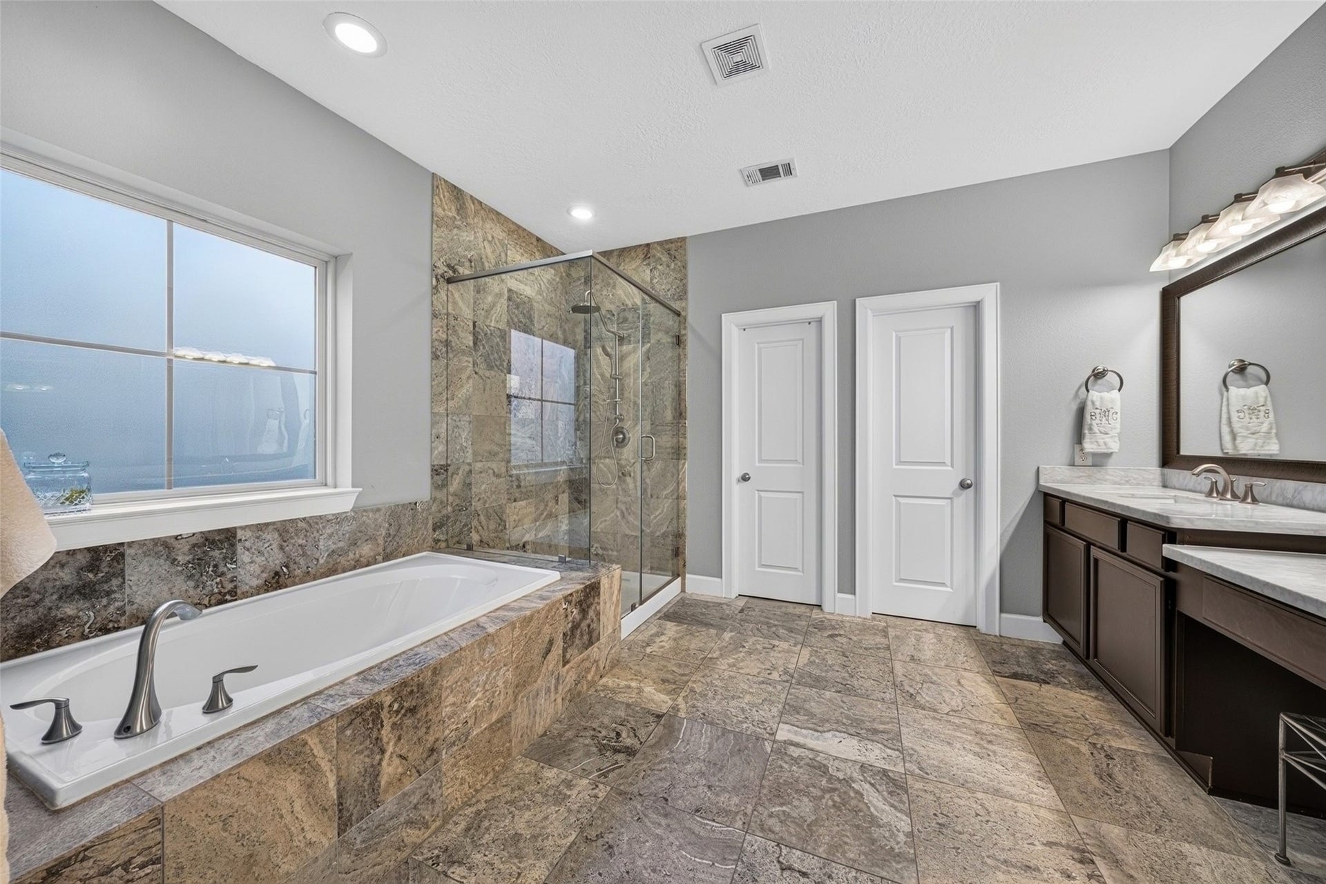 2602 Ashland Street, Houston, TX 77008 Primary bath highlighting the soaking tub, glass-enclosed shower, and elegant tile finishes.