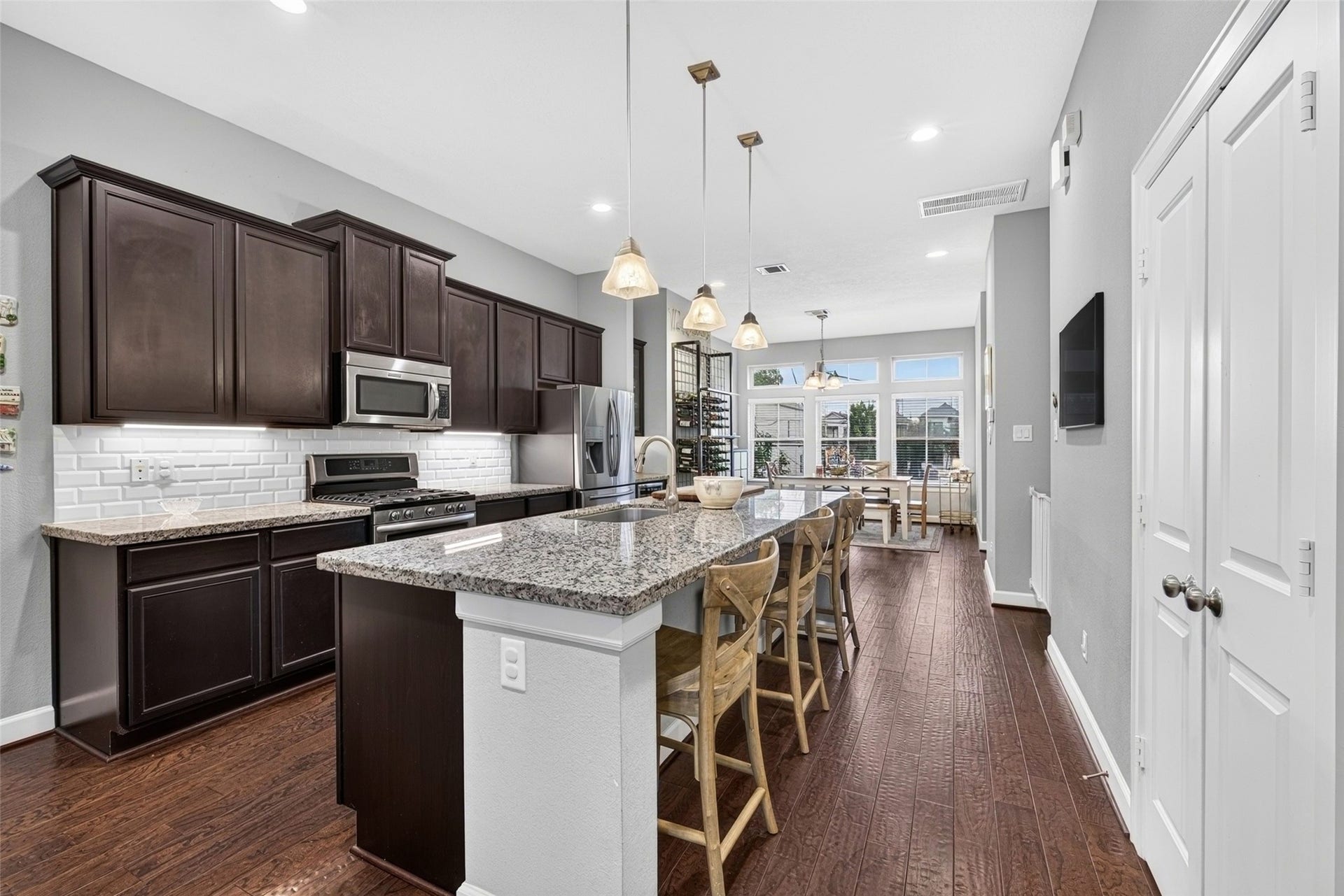 2602 Ashland Street, Houston, TX 77008 Open kitchen with granite countertops, rich wood cabinetry, stainless steel appliances, and breakfast bar seating.