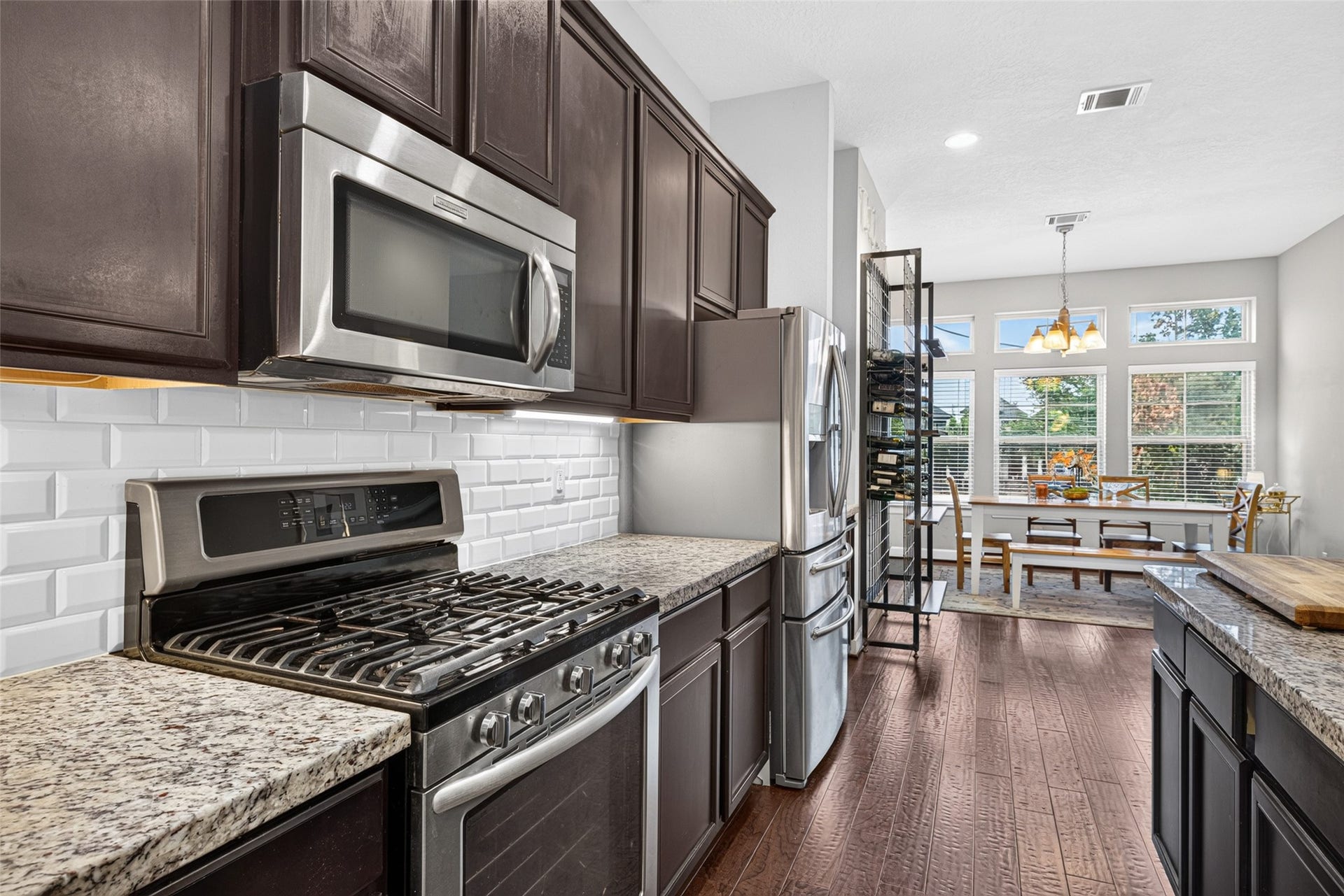 2602 Ashland Street, Houston, TX 77008 Stainless steel gas range, built-in microwave, and subway tile backsplash complement the kitchen's warm finishes.