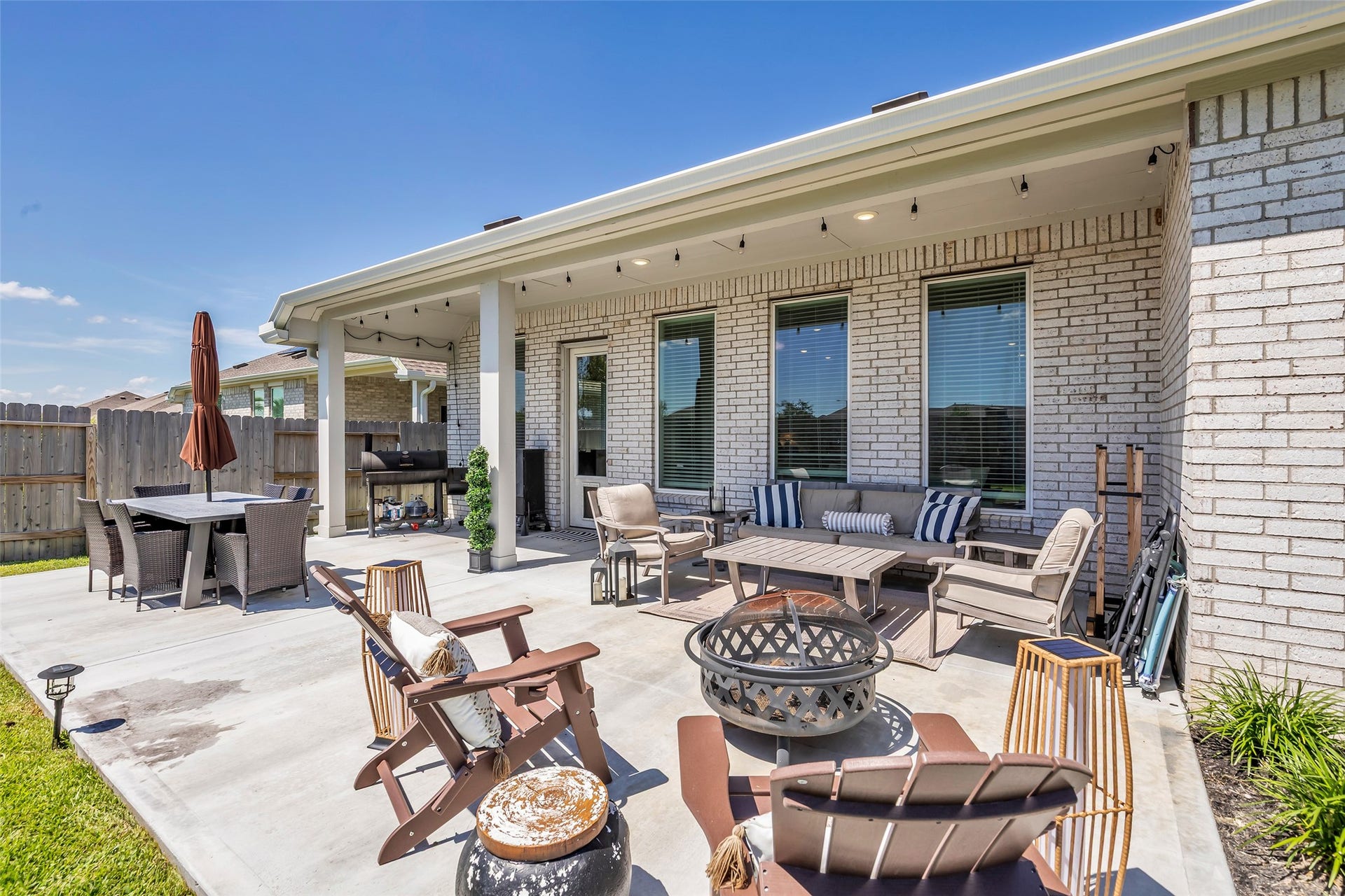 13213 Harbor Point Drive, Texas City, TX 77539 Extended outdoor patio features a spacious seating area, cozy fire pit, and dining set, perfect for entertaining or relaxing in a private fenced yard.