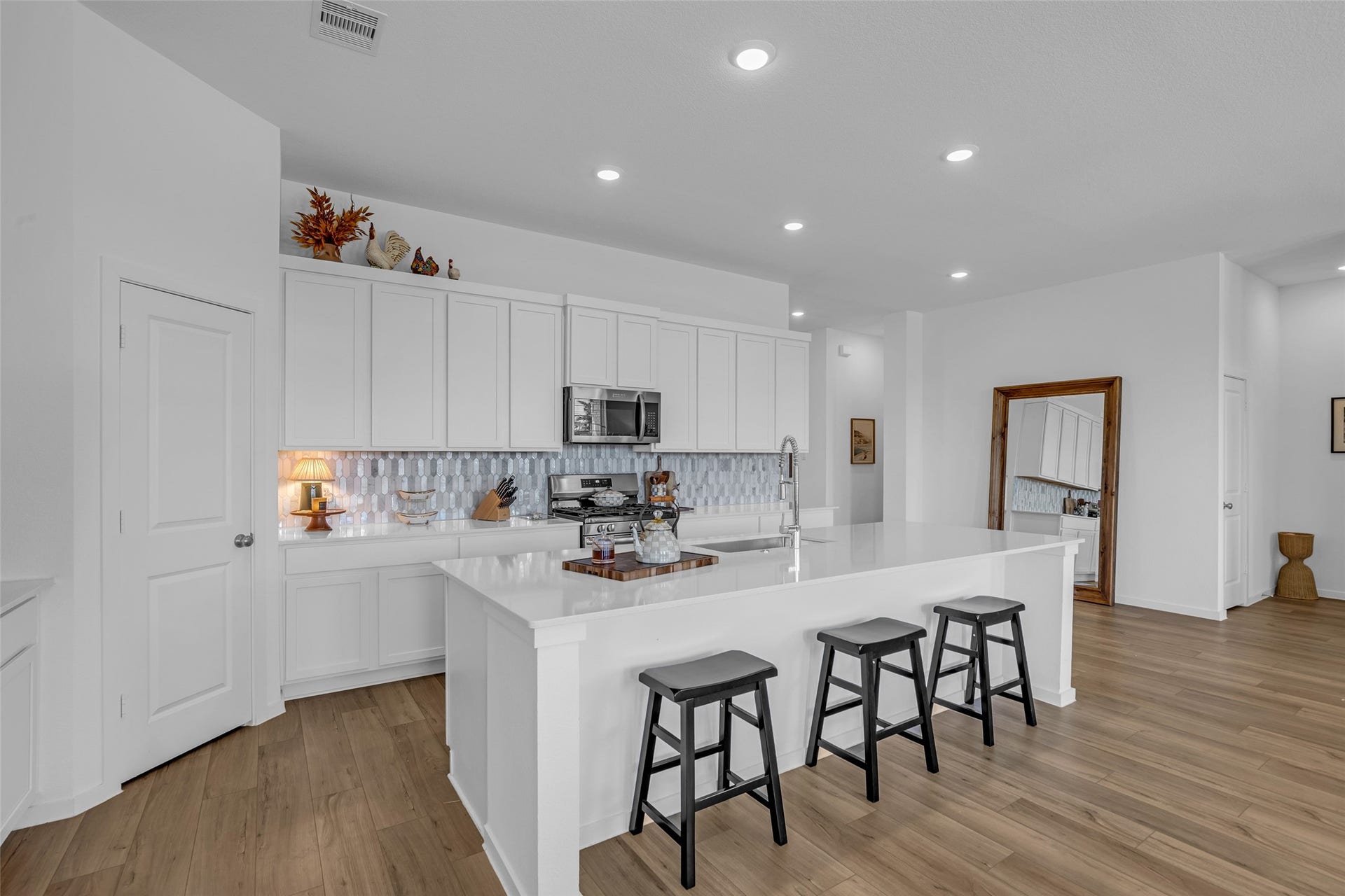 13213 Harbor Point Drive, Texas City, TX 77539 Sleek modern kitchen with white cabinetry, elegant tile backsplash, and a spacious island with seating, perfect for cooking and entertaining.
